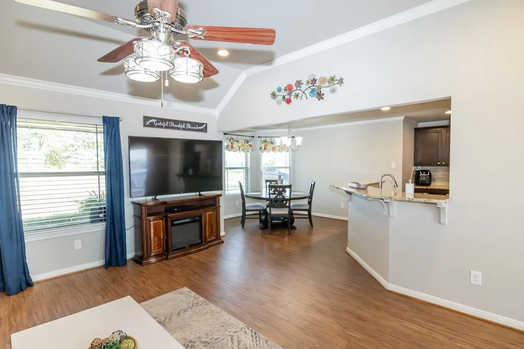 Vaulted ceiling, wood-finish flooring, kitchen pass-through with breakfast bar, granite countertop, and recessed lighting