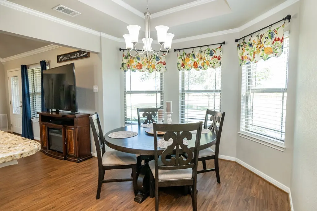 Wood-finish flooring throughout, tray ceiling, and a chandelier lighting fixture