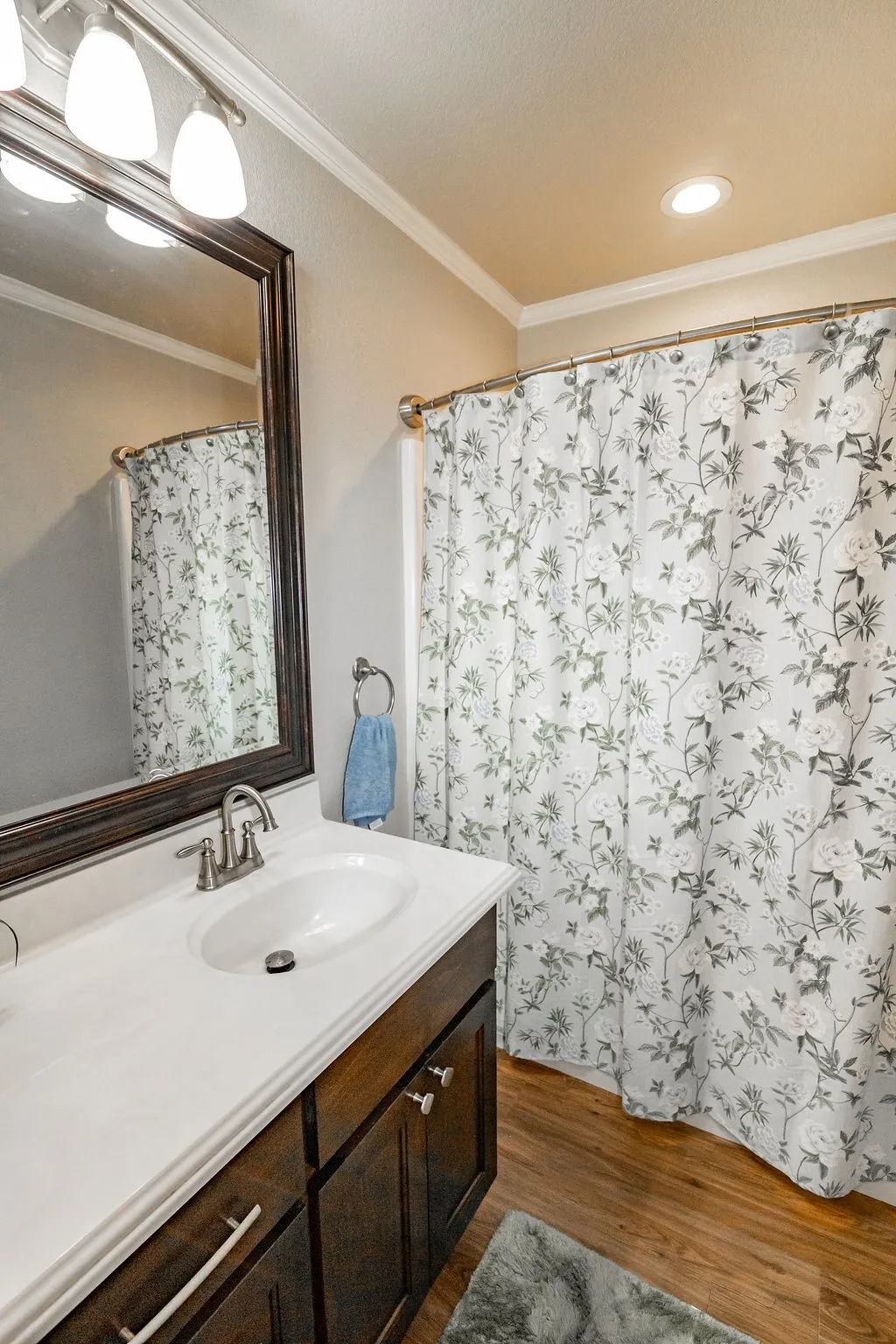 Spa-inspired bathroom featuring a white ceramic vessel sink atop a dark wood vanity with brushed nickel hardware, white quartz countertop, and framed mirror with integrated lighting