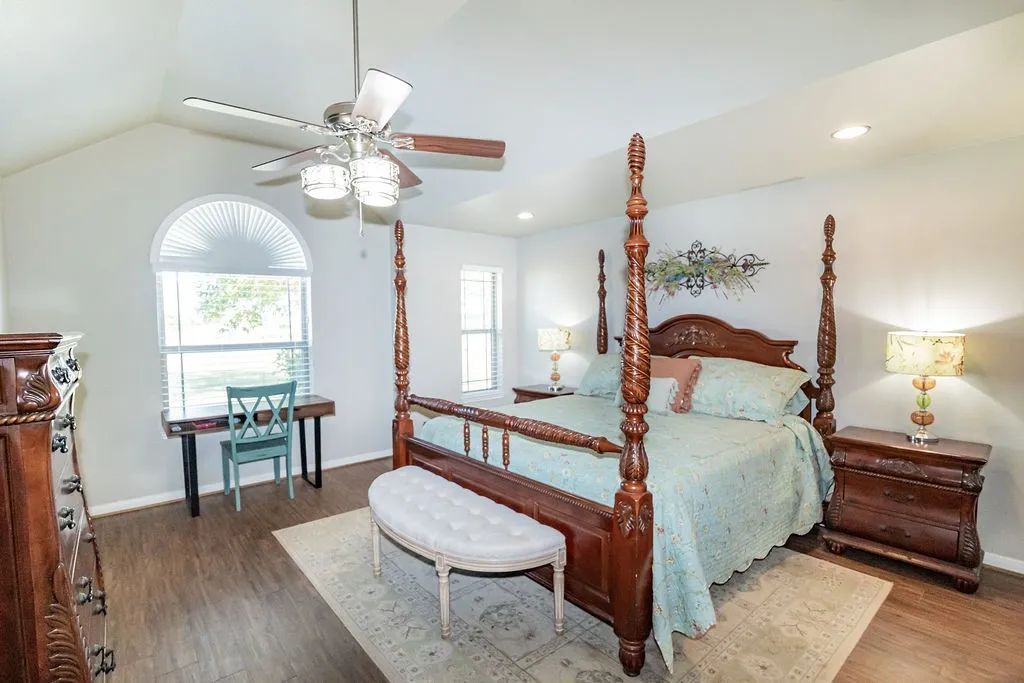 Vaulted ceiling with a ceiling fan, recessed lighting, wood-finish flooring, and arched window with blinds