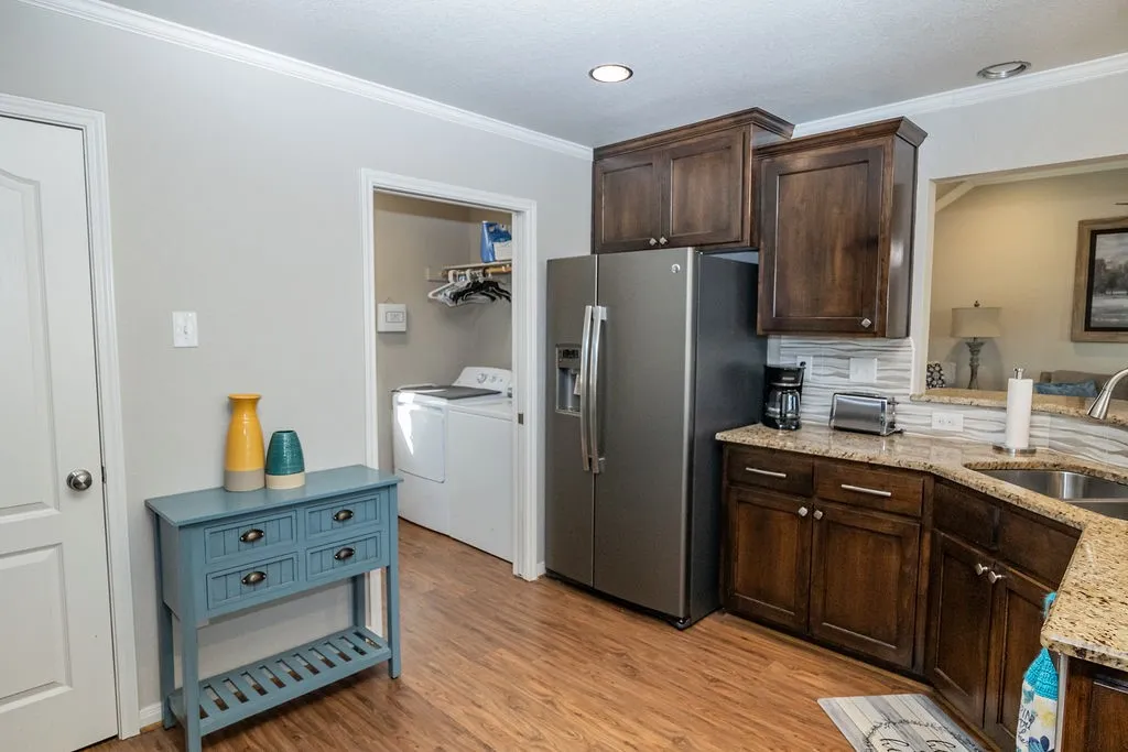 Wood-finish flooring, recessed lighting, crown molding, stainless steel refrigerator, and granite countertops