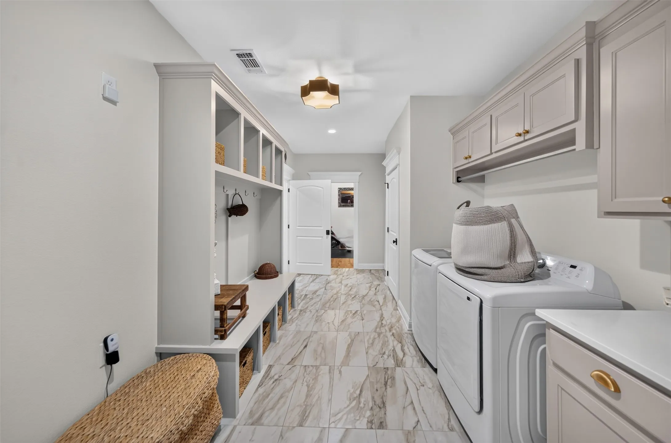 Mudroom and laundry area with built-in cubbies, bench seating, and upper cabinetry