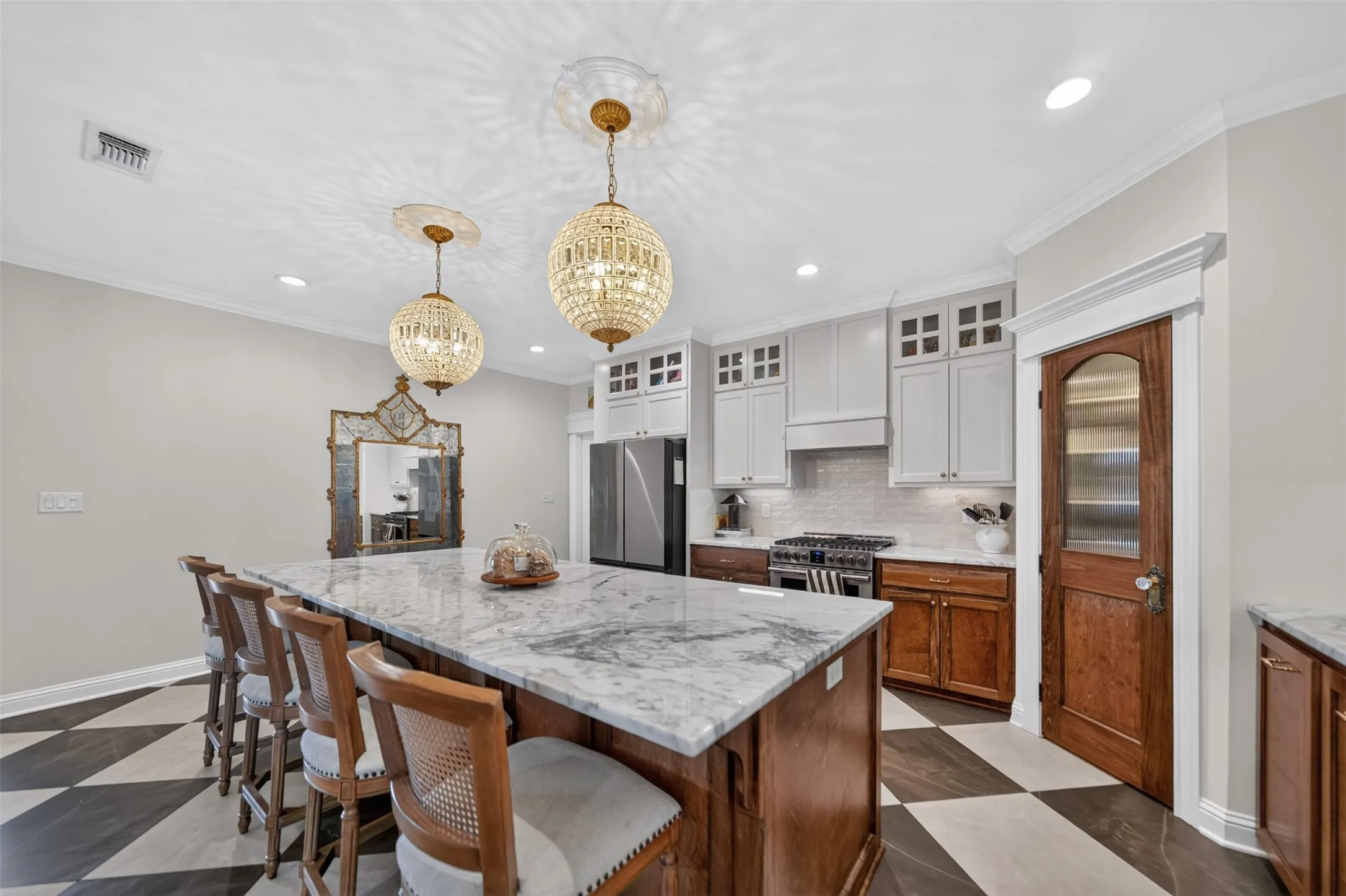 Spacious kitchen featuring a large island with a stone countertop, checkered tile flooring, stainless steel appliances, and custom cabinetry