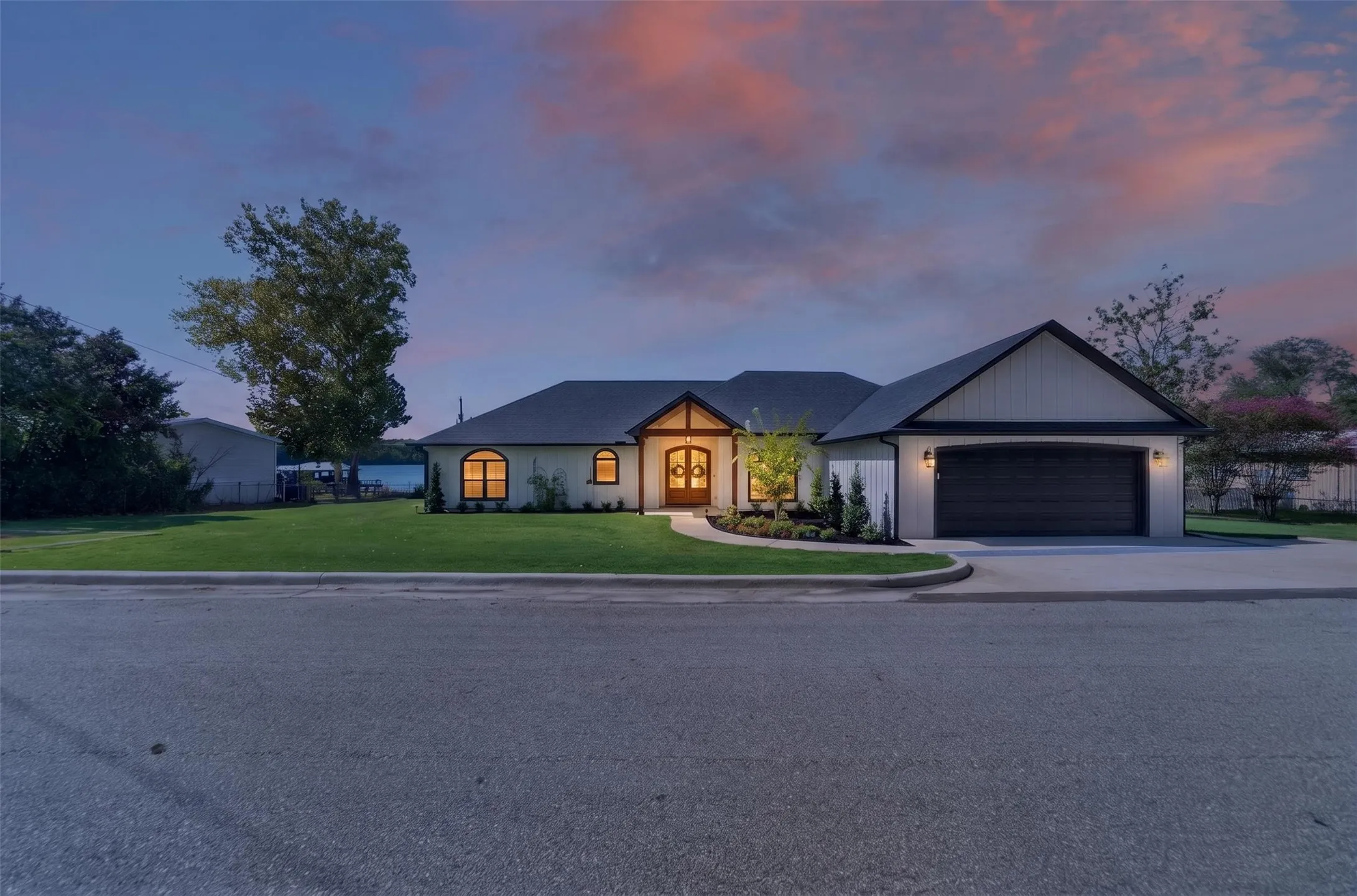 Contemporary single-story residence with a black shingle roof, two-car garage, and arched windows