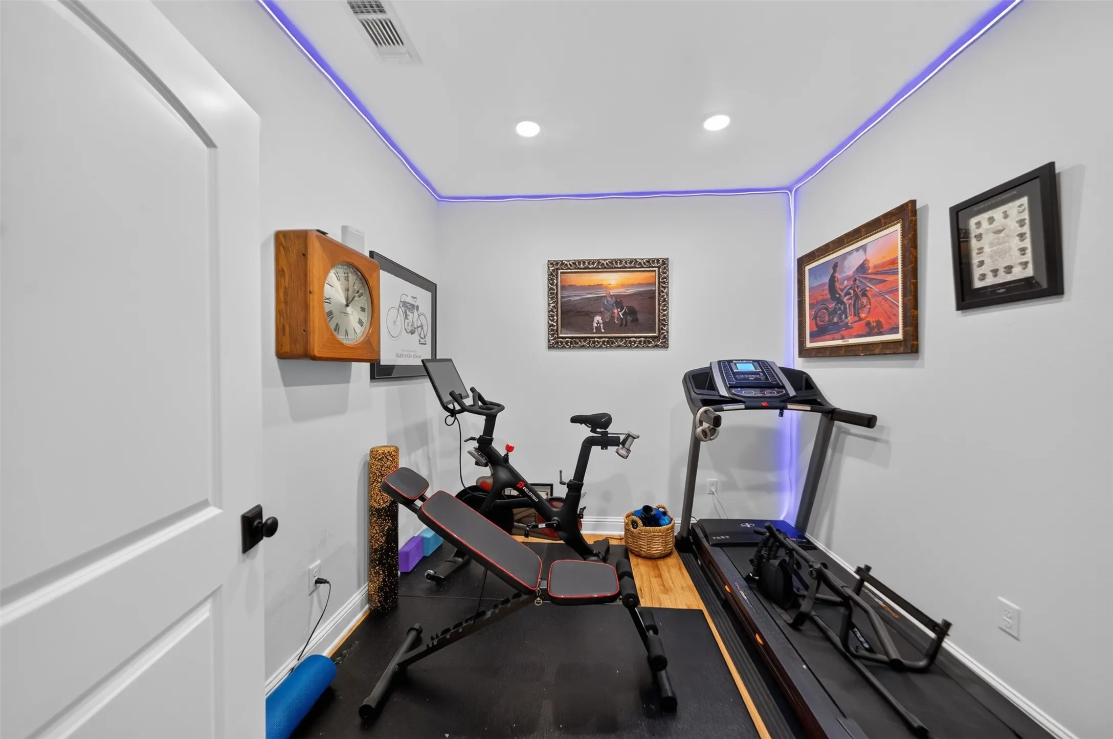 Recessed lighting, ceiling-mounted perimeter lighting, white paneled door with black hardware, and light gray wall paint