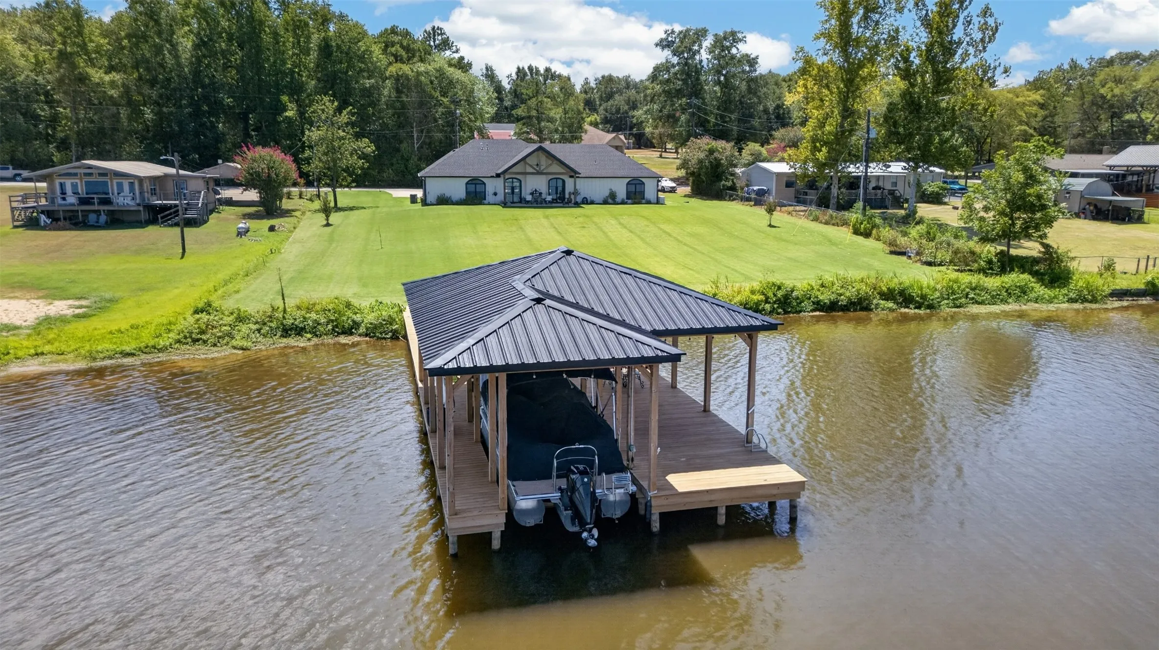 Waterfront boathouse featuring a metal roof, covered dock with concrete decking, and direct water access