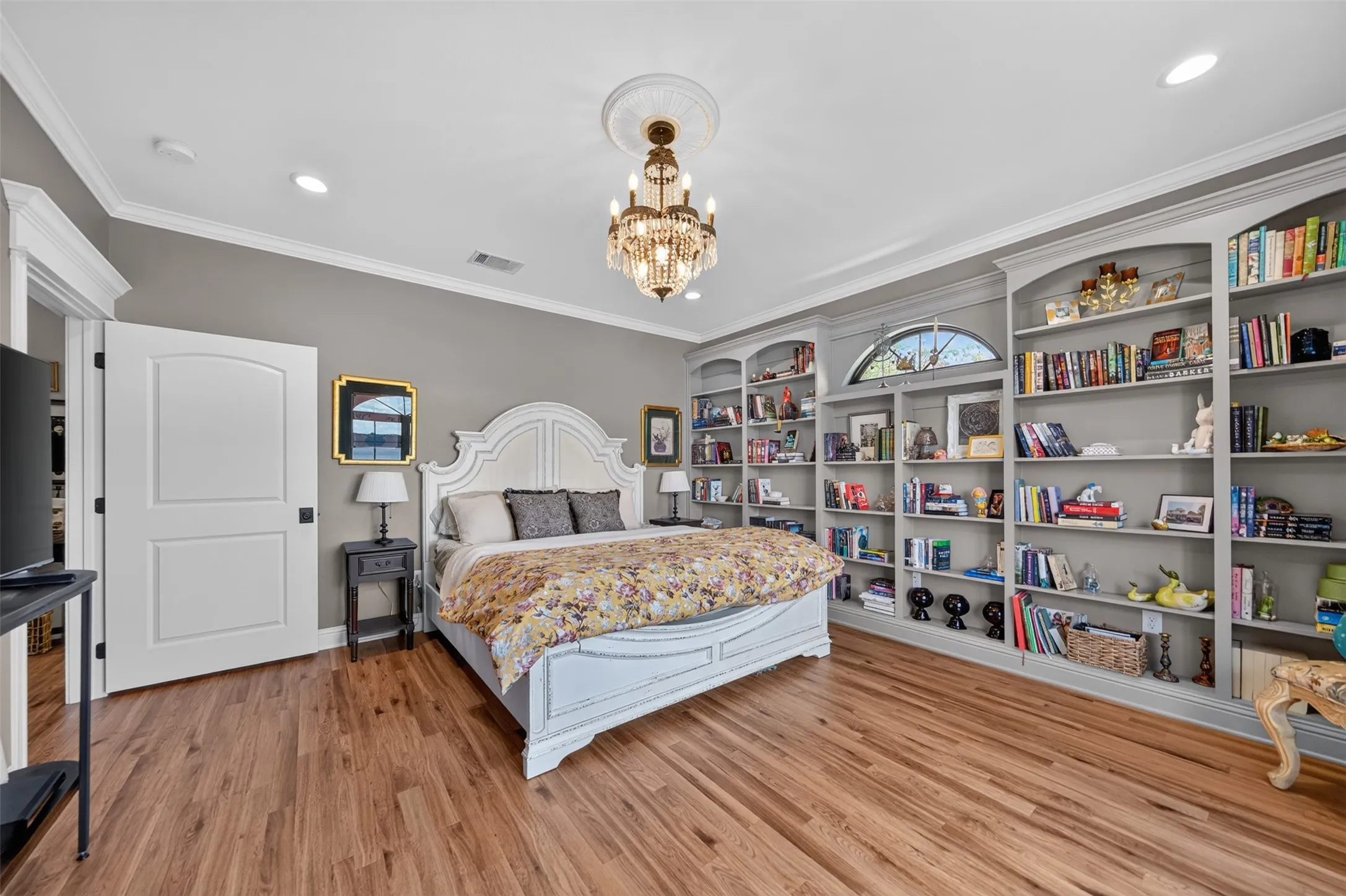 Hardwood flooring, crown molding, built-in shelving, recessed lighting, and a crystal chandelier