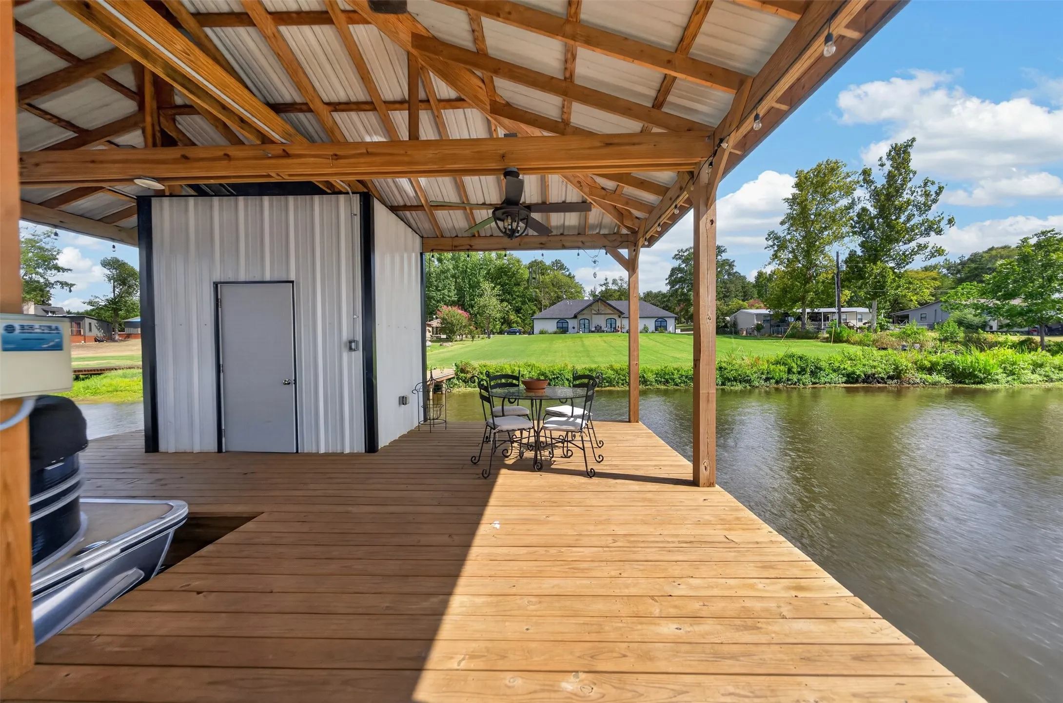 Waterfront deck featuring premium wood-finish decking beneath a substantial wooden pergola with corrugated metal roofing