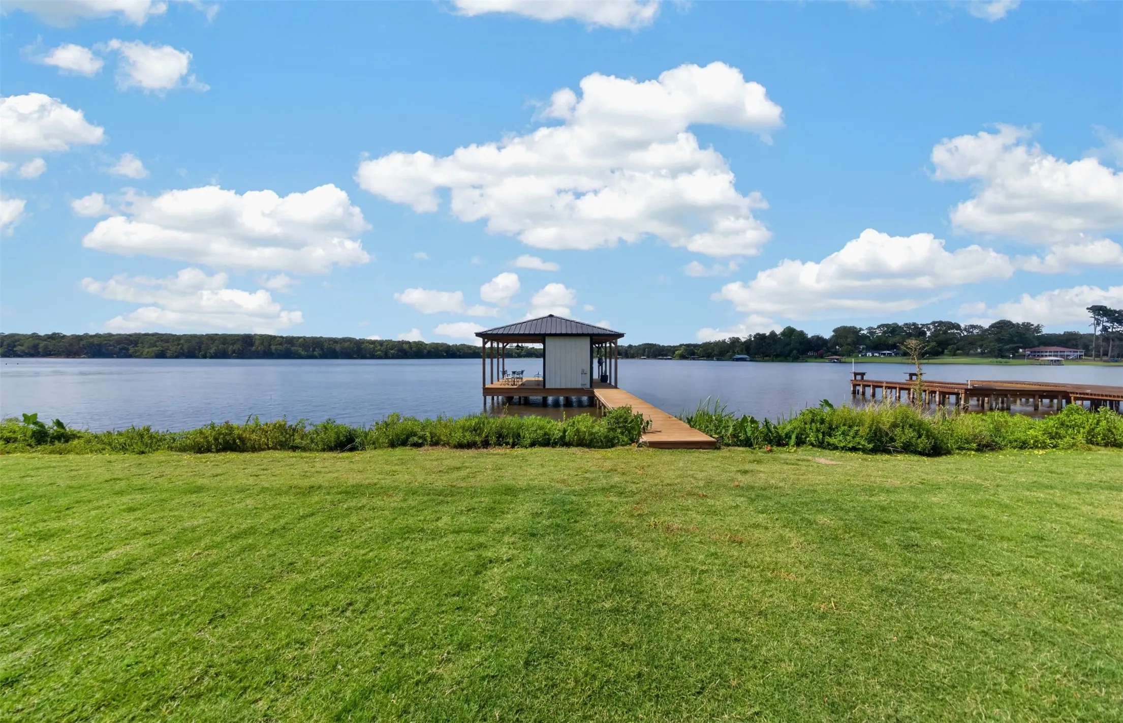 Expansive lawn featuring waterfront access with a private covered dock