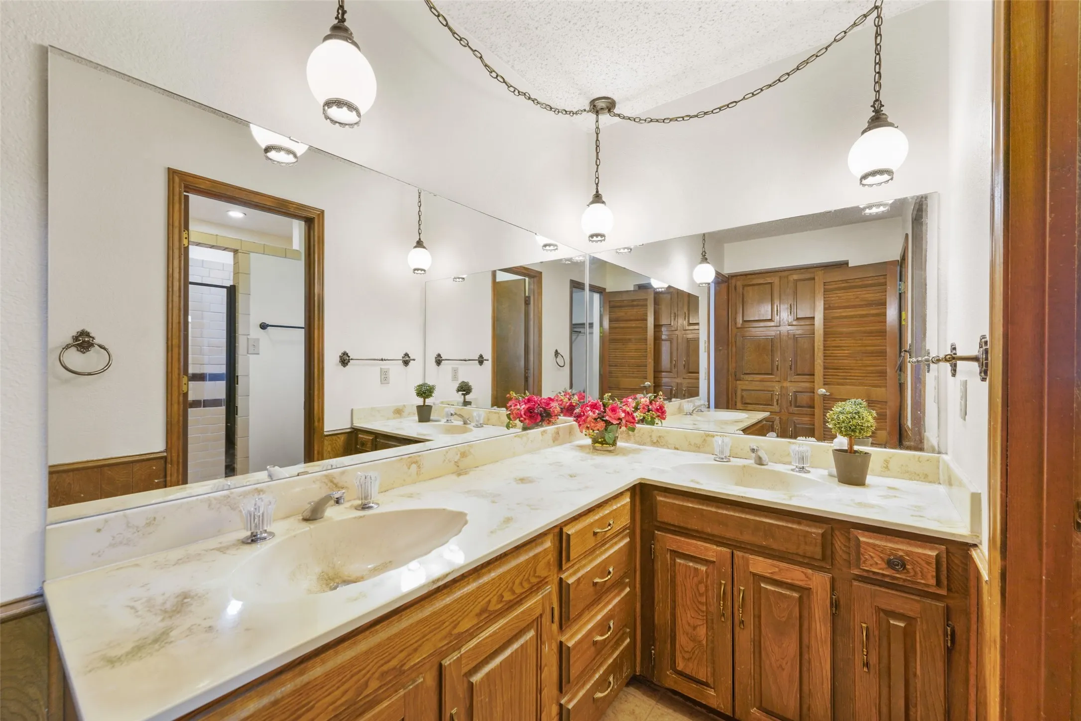U-shaped vanity with integrated sinks, stone-finish countertop, wood cabinetry, and extensive wall mirror