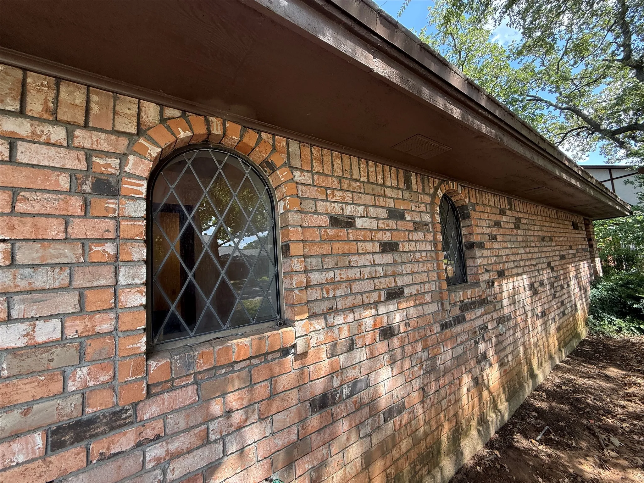 Brick exterior with arched leaded glass windows and a wide eave