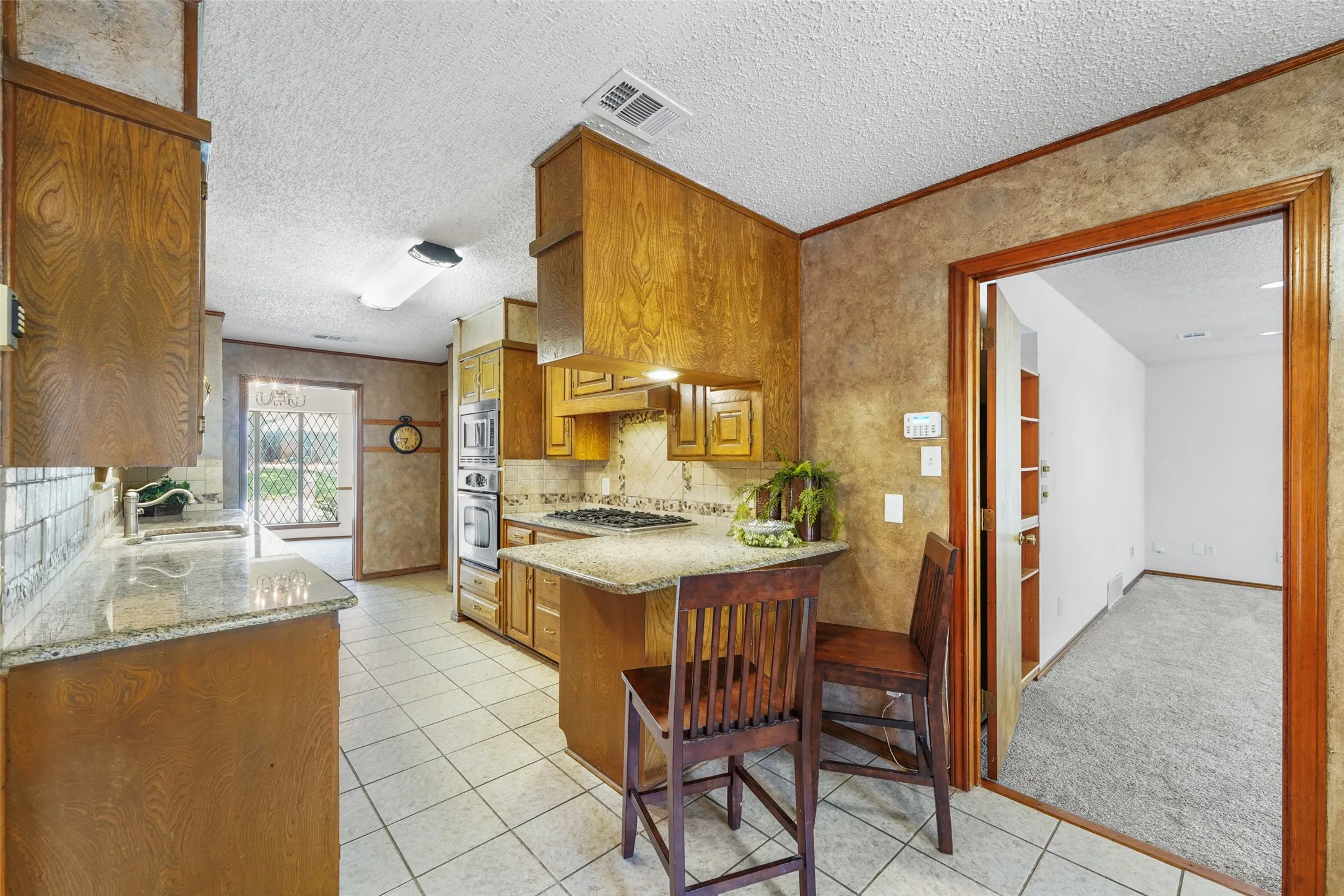 Kitchen featuring wood cabinetry, light-toned countertop surfaces, stainless steel built-in appliances, and tile flooring