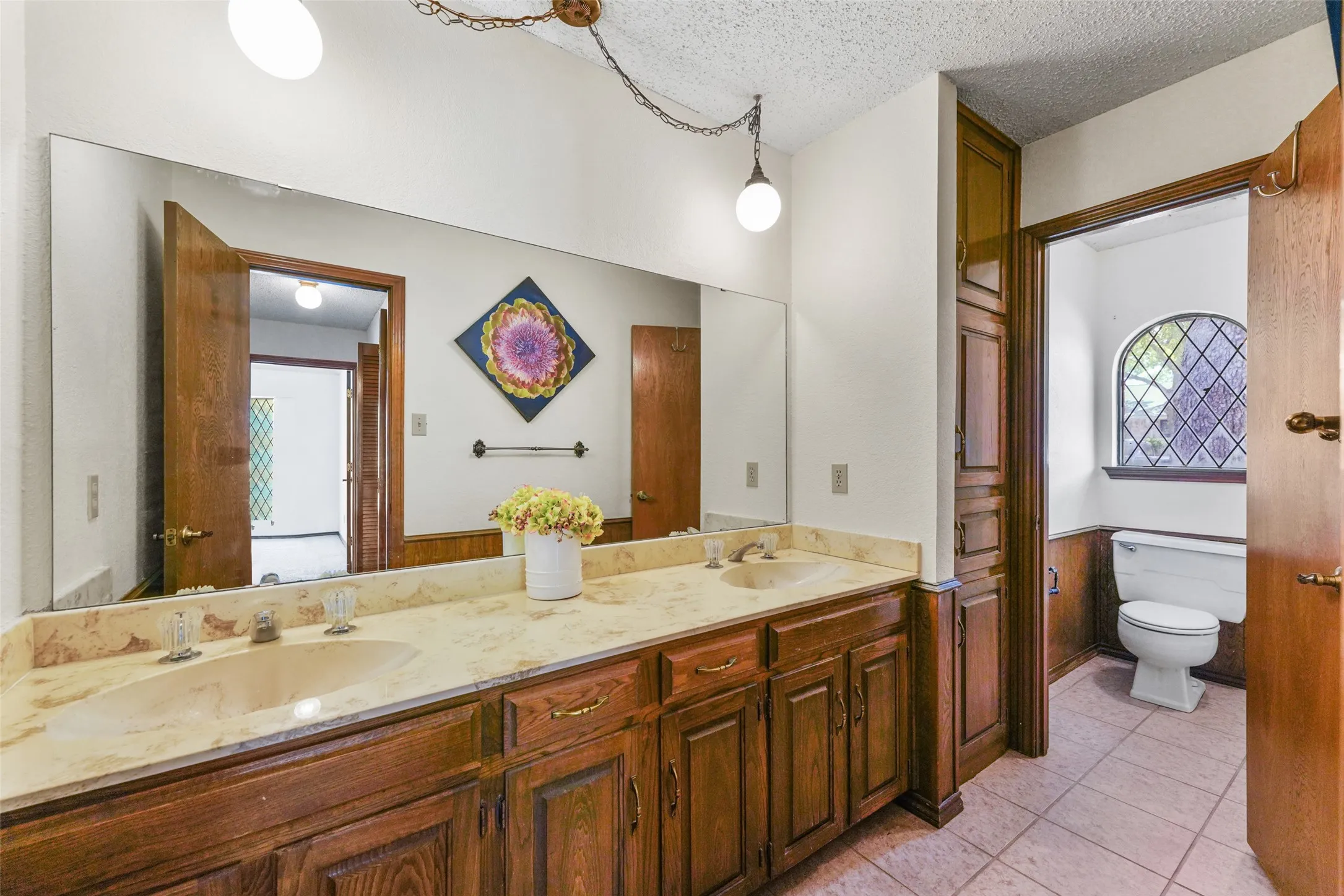 Dual vanity with light-toned countertop, wood-finish cabinetry, and built-in storage