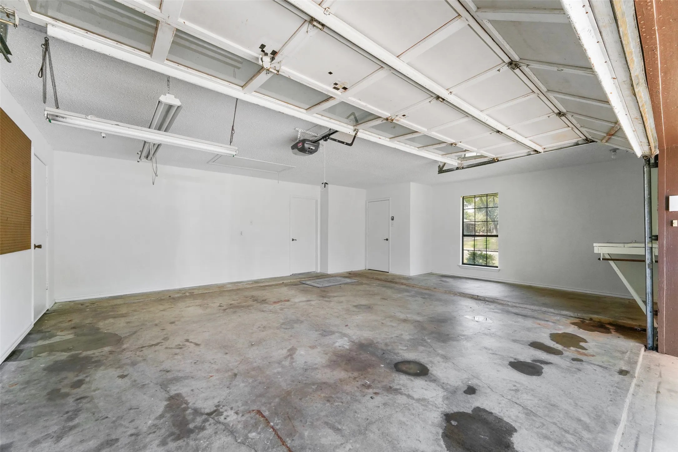 Garage space with concrete flooring, fluorescent overhead
lighting, and a single window with a great workspace counter top