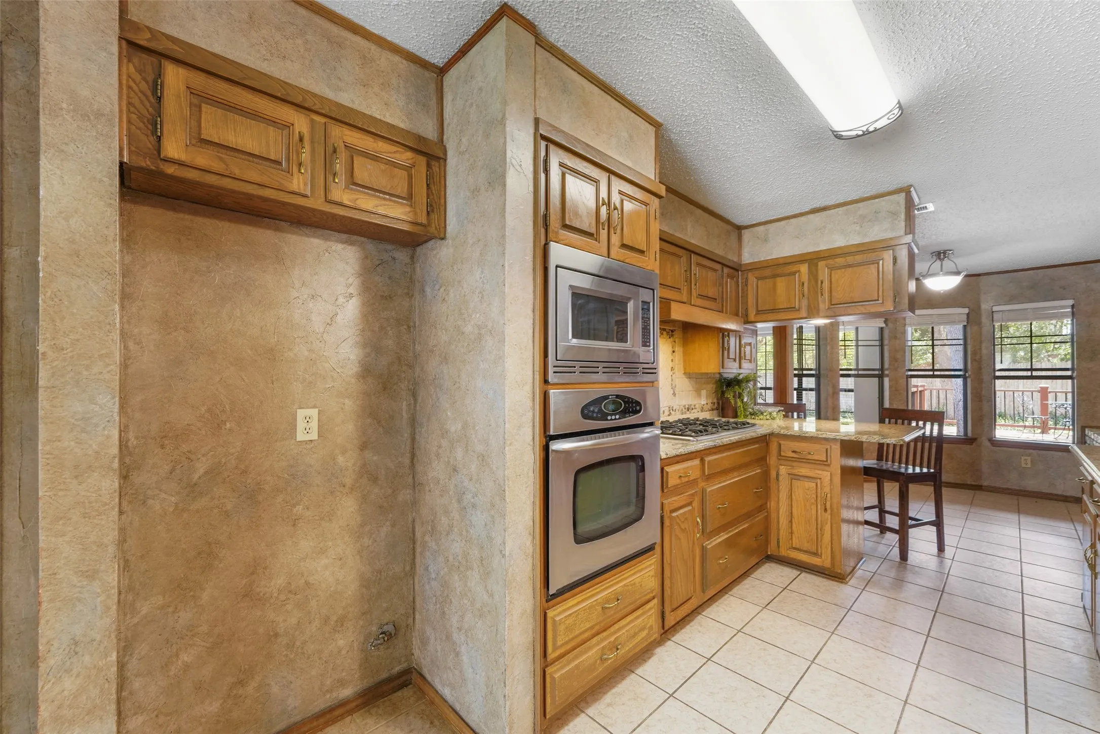 Kitchen featuring wood cabinetry, stainless steel appliances, tile flooring, and a built-in breakfast bar