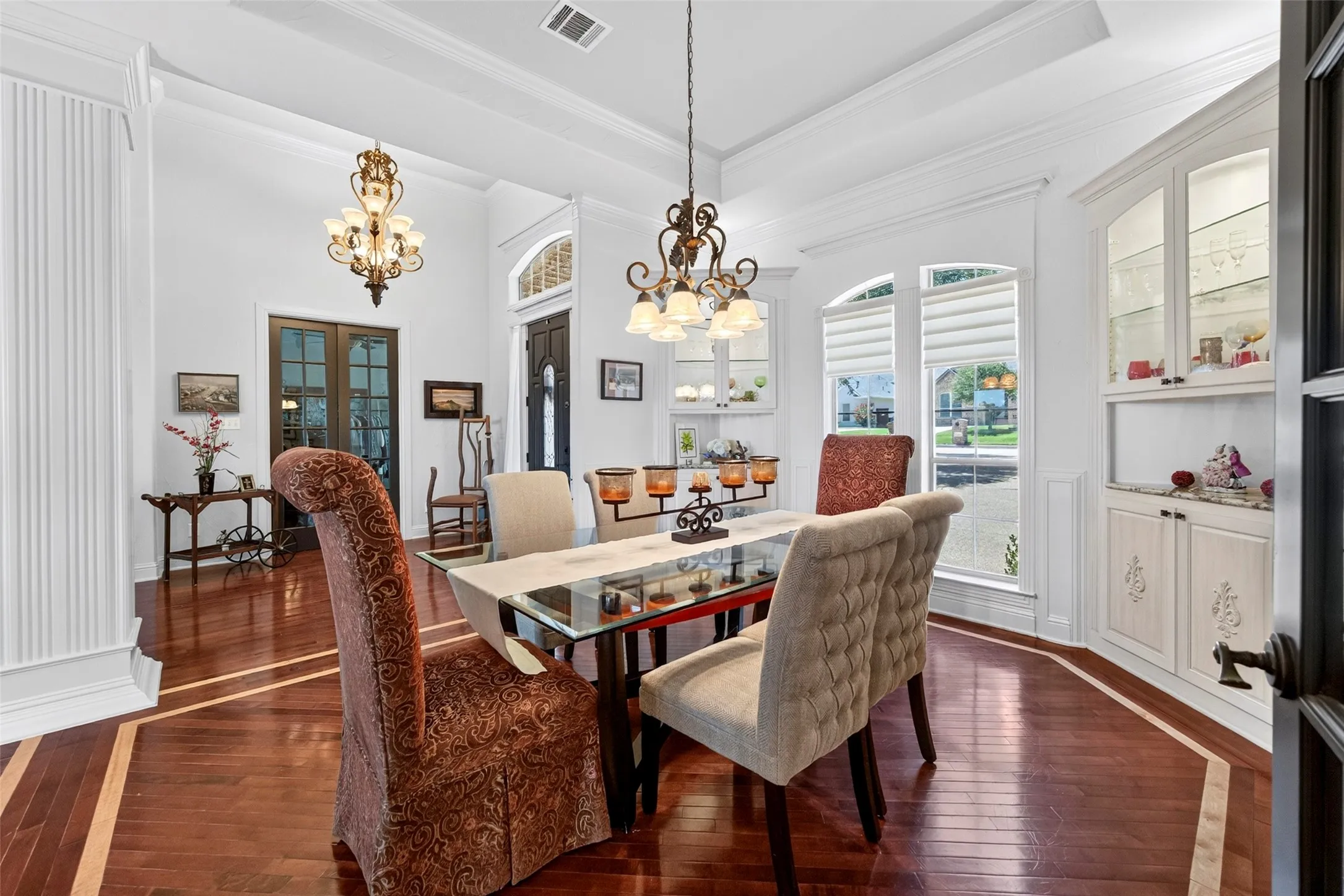 Formal dining area featuring built-in glass front corner cabinets and inlaid wood floor