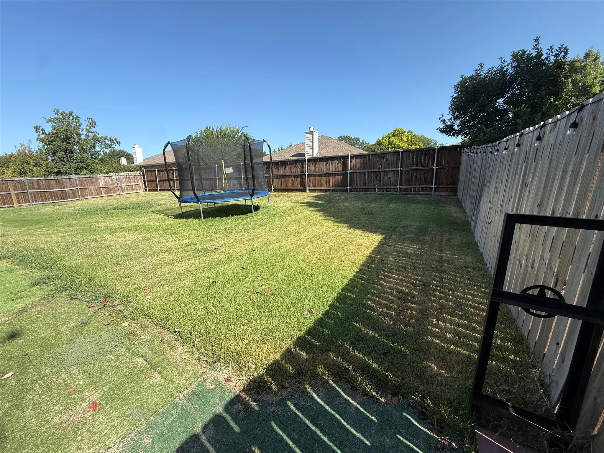 Expansive backyard featuring a lush lawn, privacy fencing, and mature trees