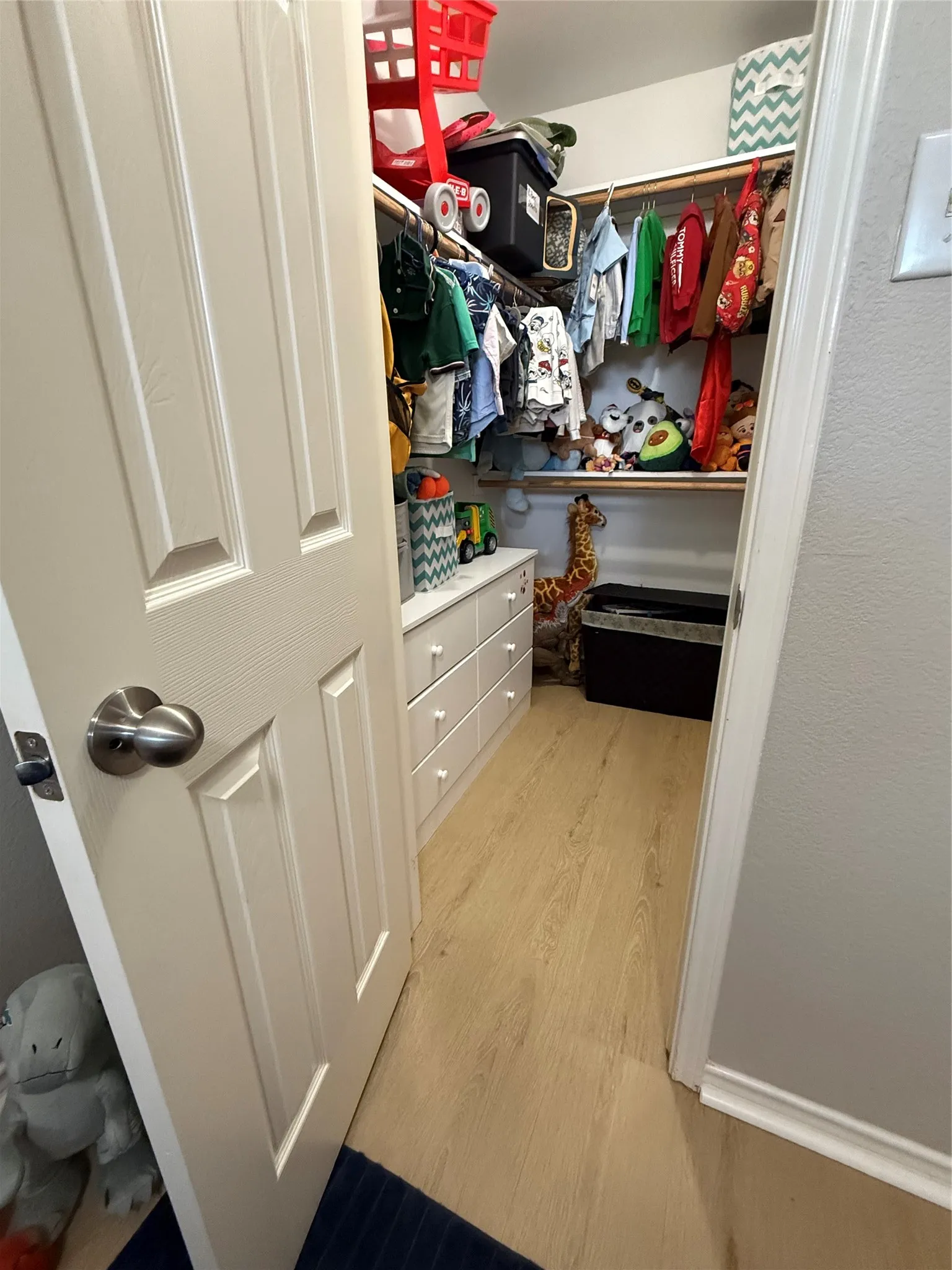 Walk-in closet with built-in shelving, hanging rods, and wood-finish flooring