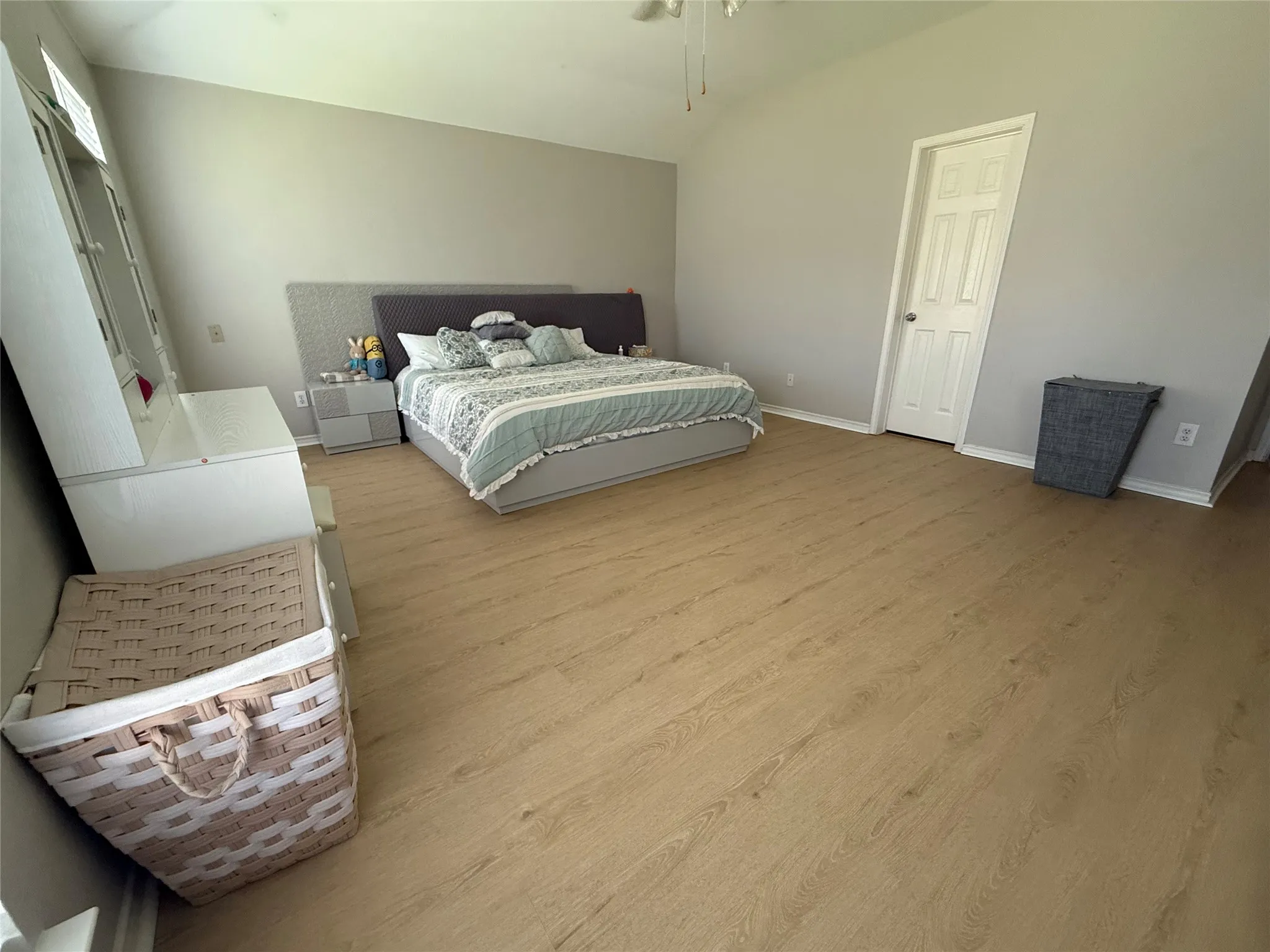 Vaulted ceiling, ceiling fan, wood-finish flooring, paneled door, built-in shelving unit