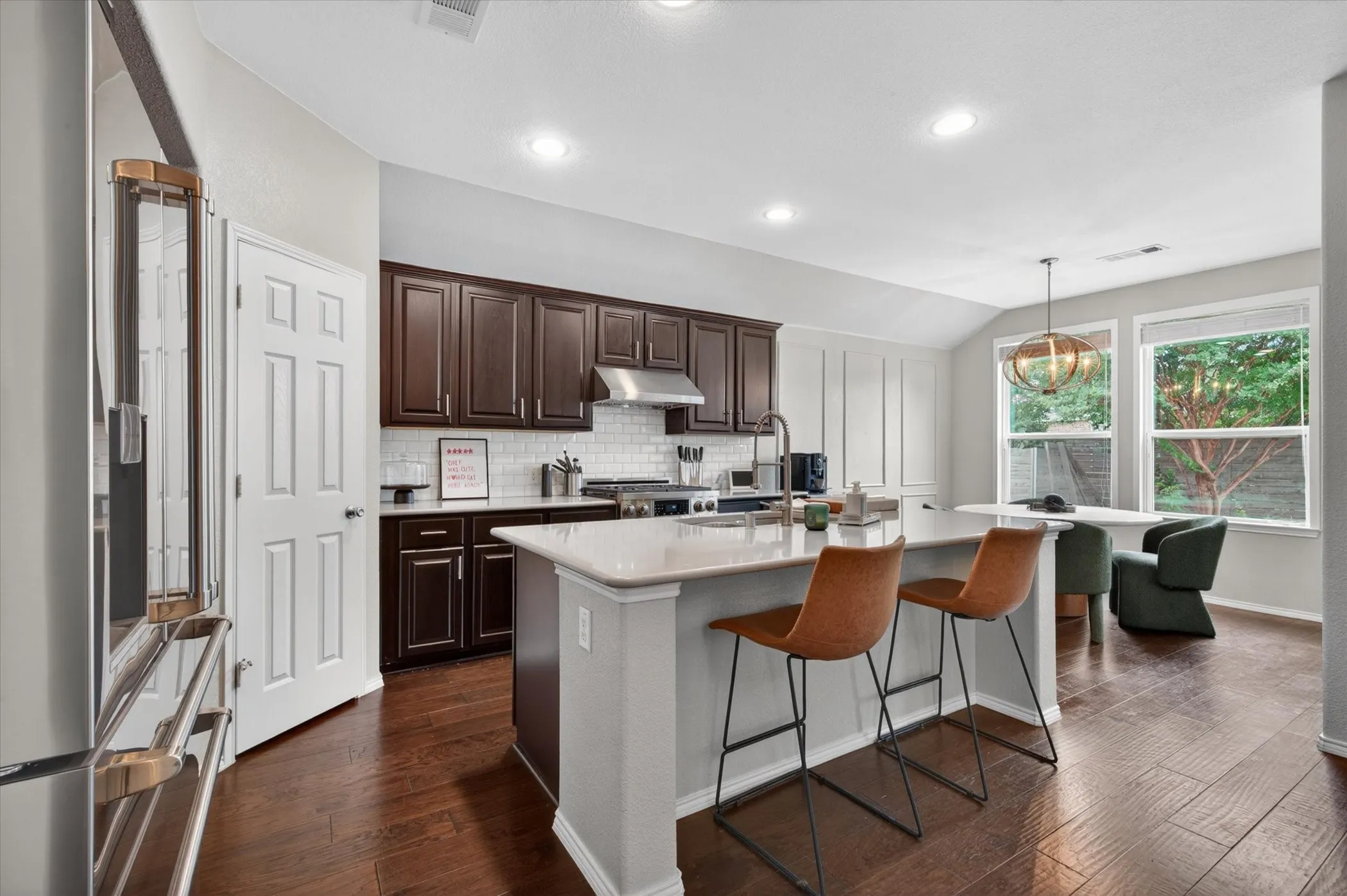 Modern kitchen featuring dark wood cabinetry, stainless steel appliances, and a white quartz island with waterfall edge