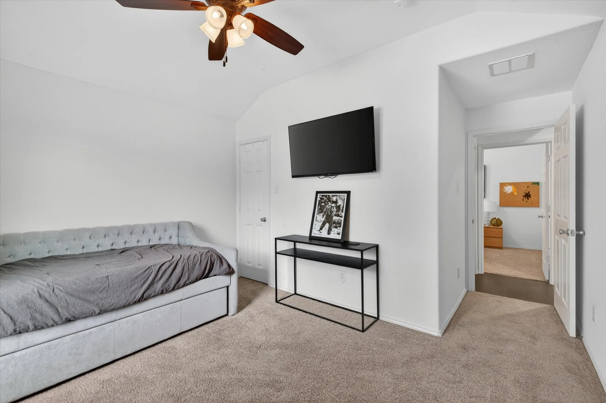 Carpeted room with a ceiling fan light fixture, white walls, and a white interior door