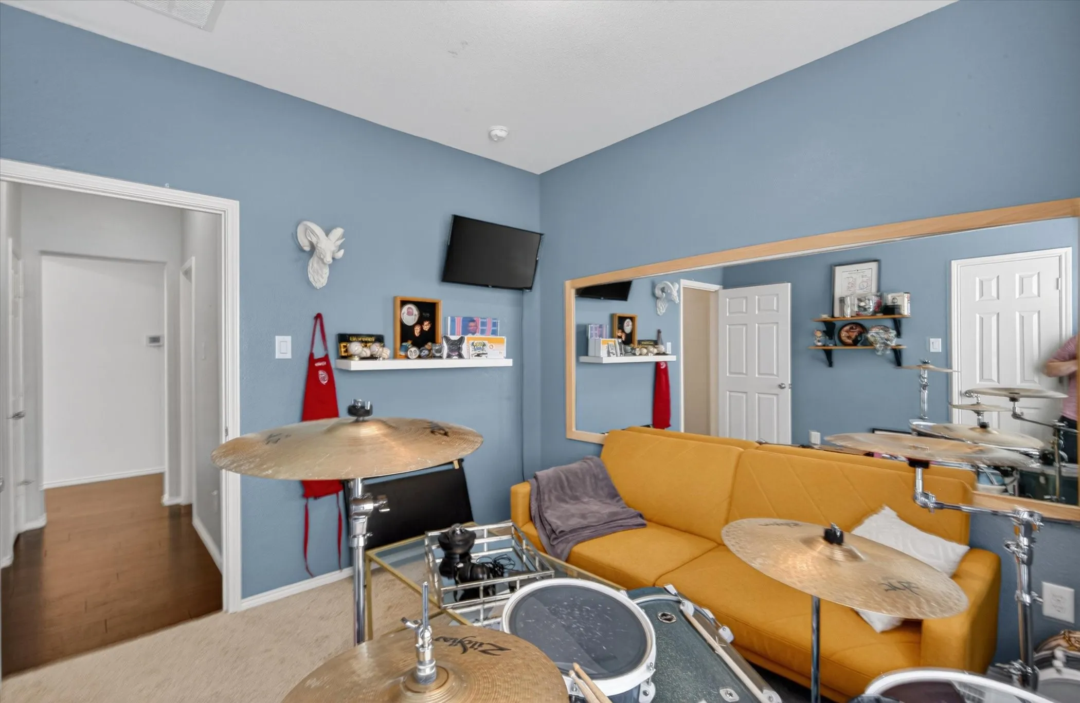Multipurpose room with light blue painted walls, carpeted flooring, and a large wall-mounted mirror with a natural wood frame