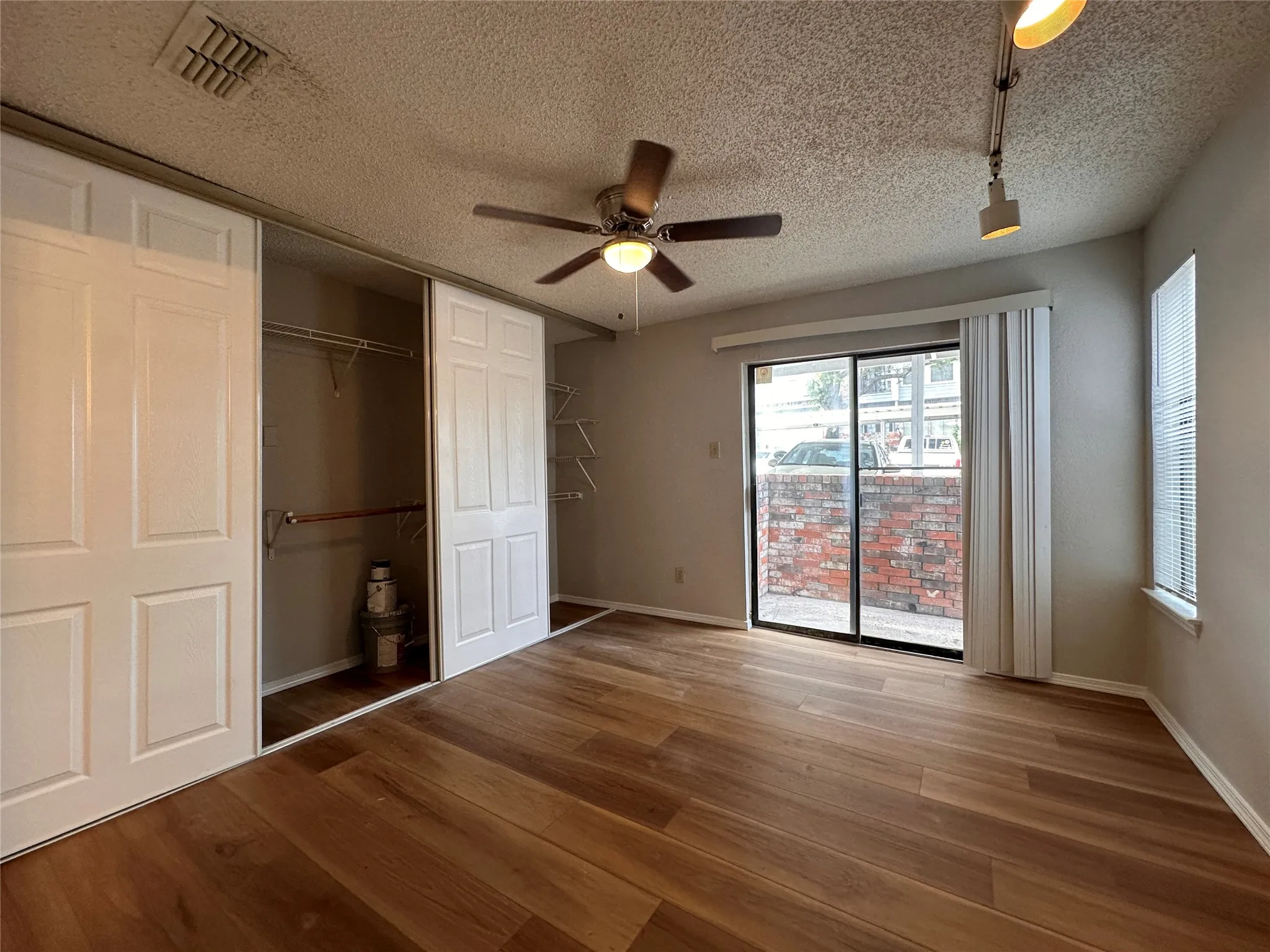 Unfurnished bedroom with ceiling fan, hardwood / wood-style flooring, and a textured ceiling