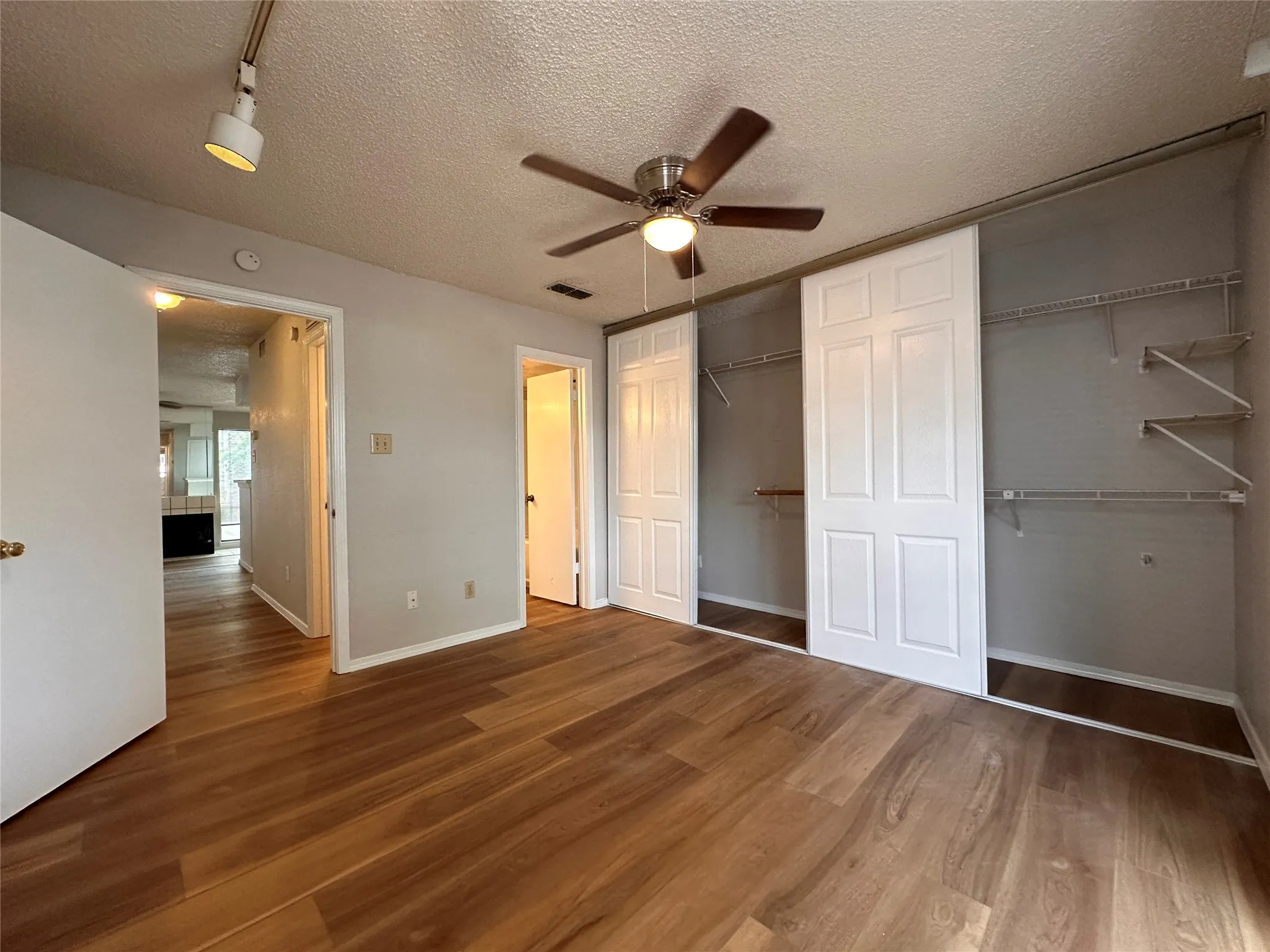 Unfurnished bedroom featuring dark hardwood / wood-style flooring, ceiling fan, and a textured ceiling