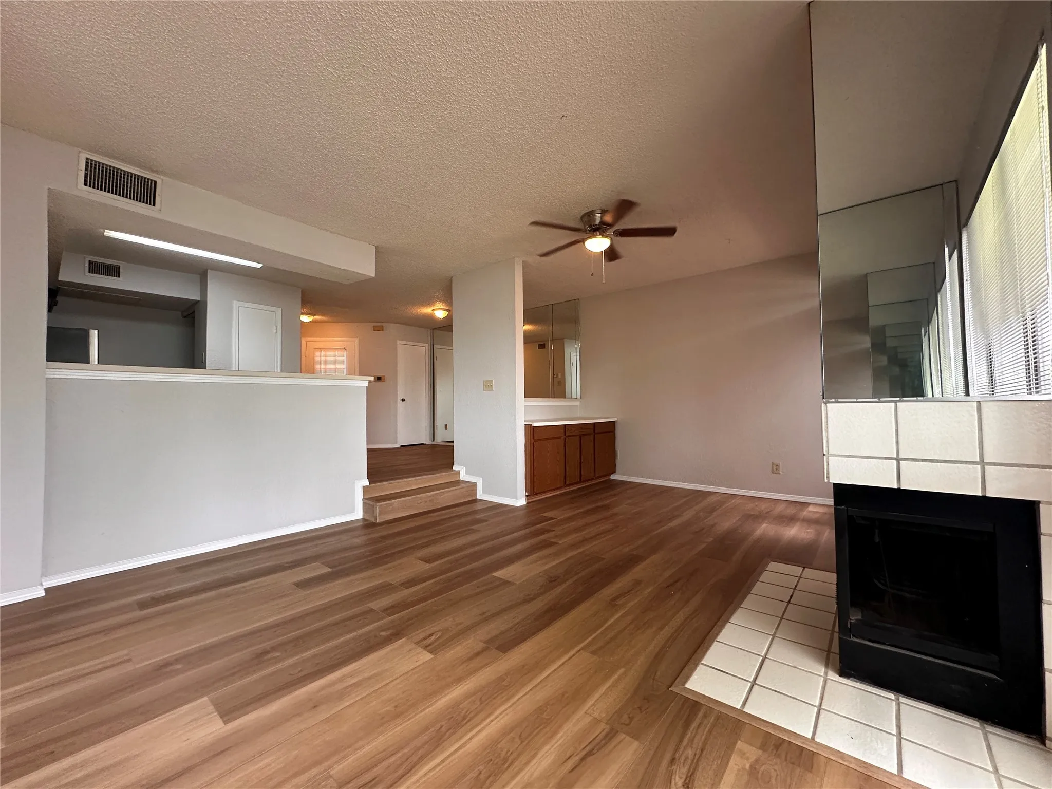 Unfurnished living room with ceiling fan, a textured ceiling, and light wood-type flooring