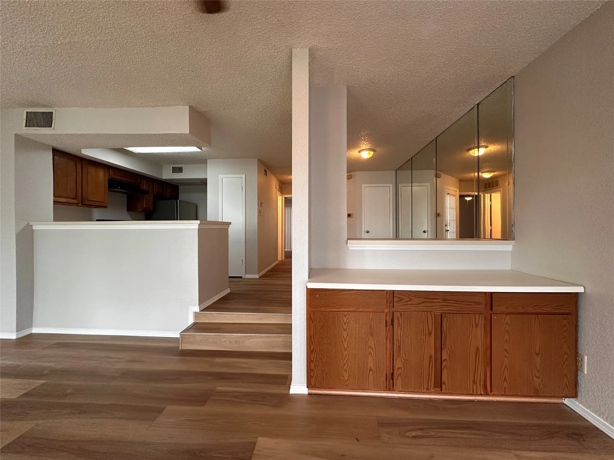 Kitchen with range hood, hardwood / wood-style floors, a textured ceiling, and fridge