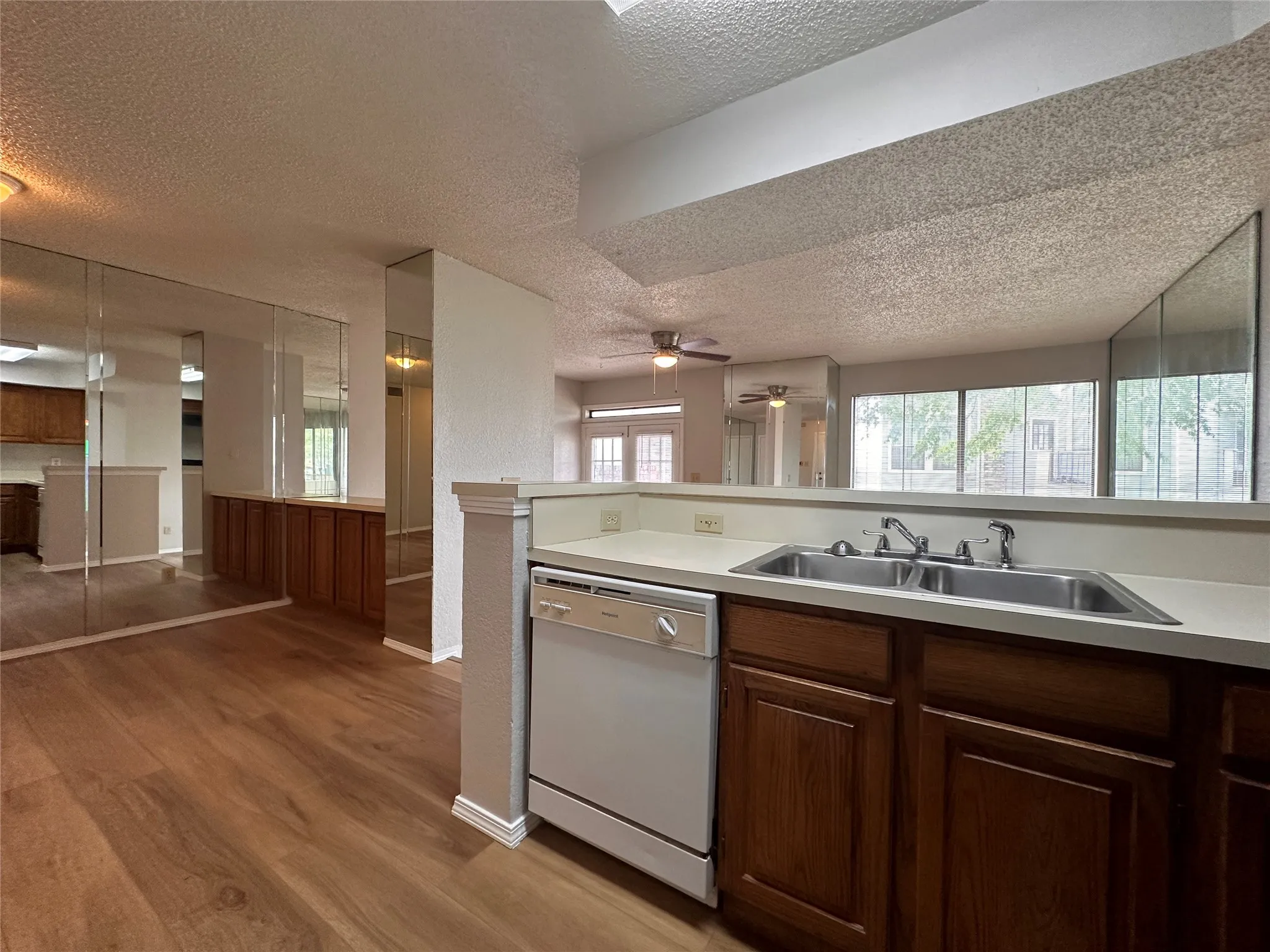 Kitchen featuring ceiling fan, a textured ceiling, sink, light hardwood / wood-style flooring, and white dishwasher