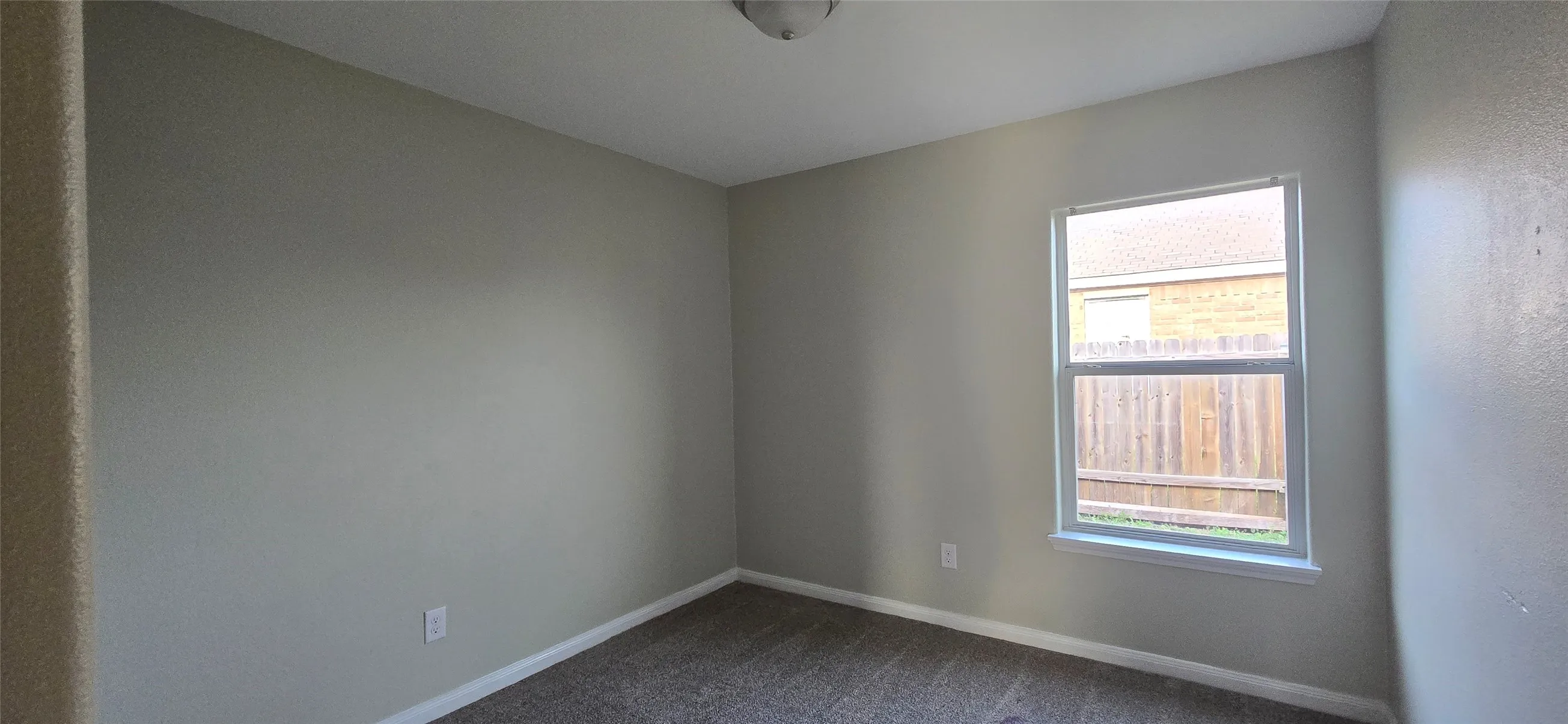 Spare room with baseboards and dark carpet