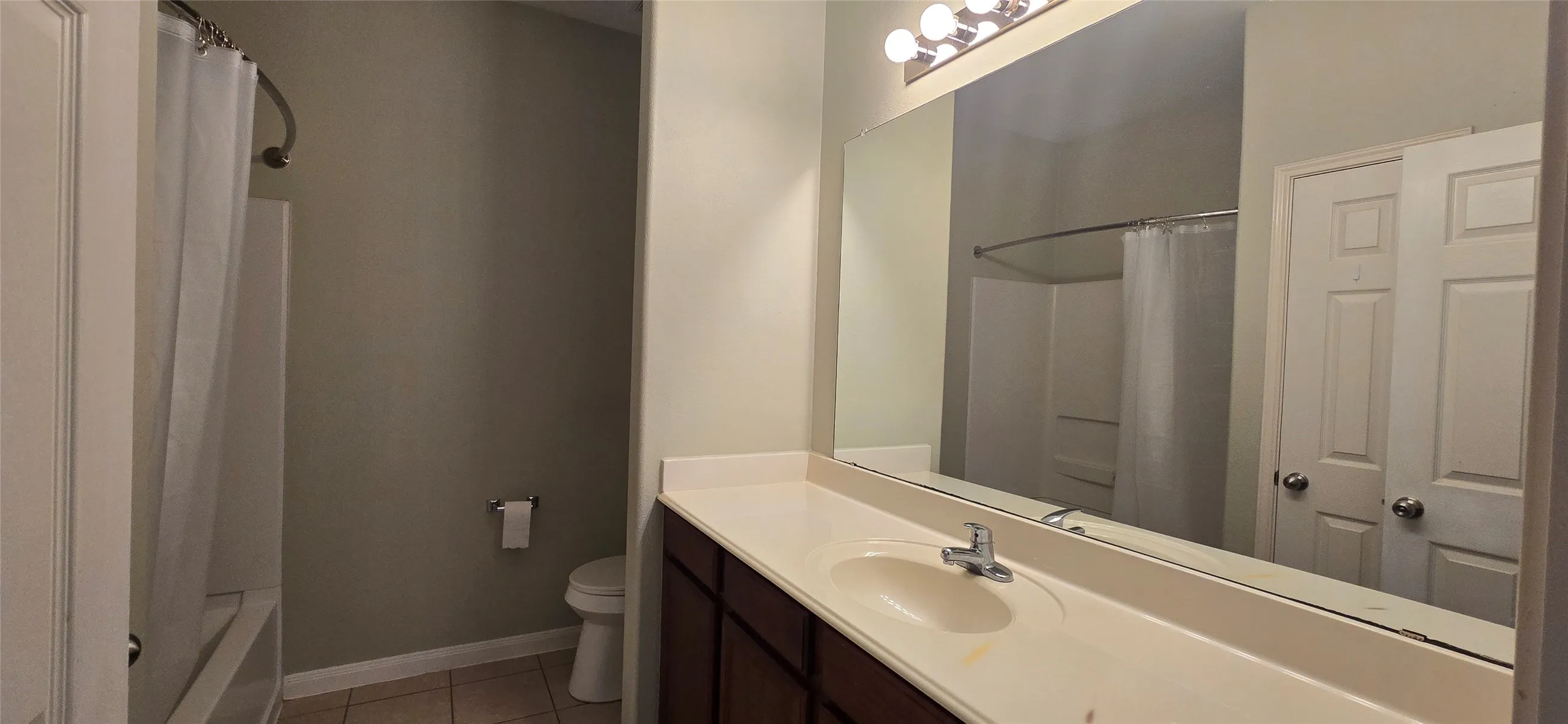 Bathroom featuring tile patterned floors, toilet, vanity, and baseboards