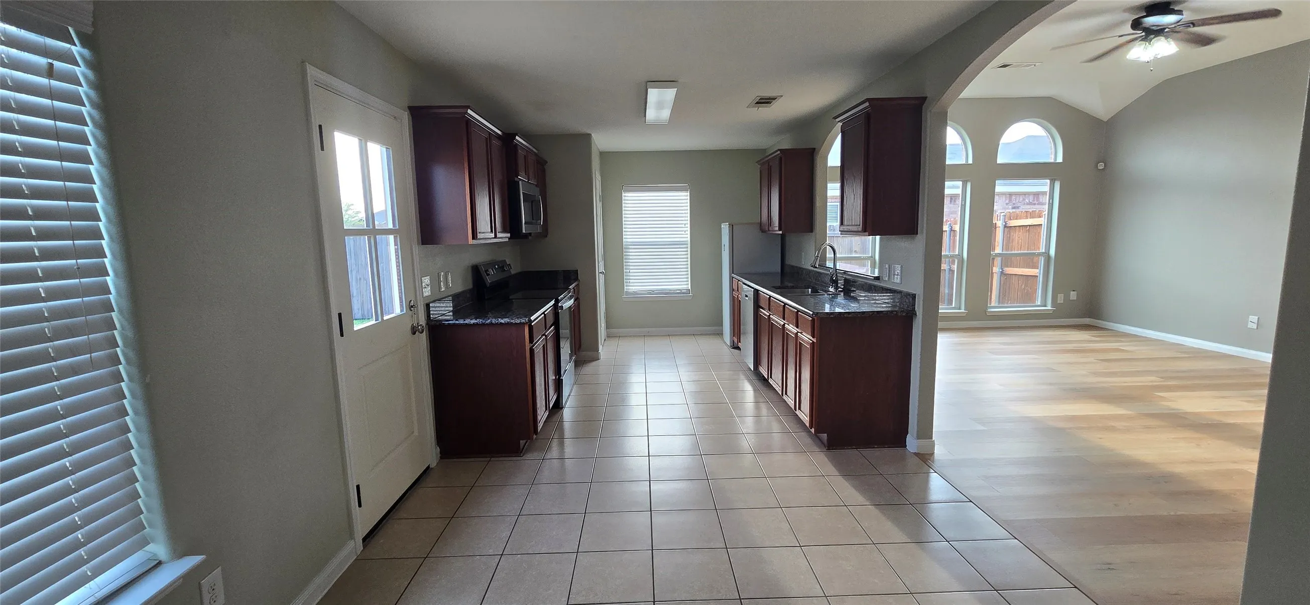 Kitchen featuring visible vents, stainless steel appliances, a ceiling fan, a sink, and light tile patterned floors