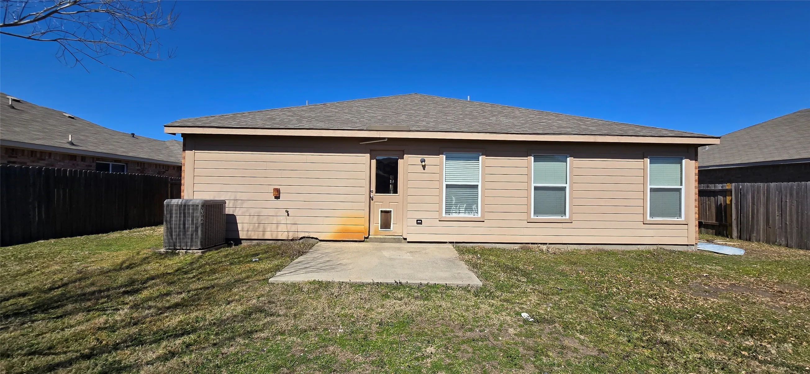 Back of house featuring a fenced backyard, central AC unit, and a yard