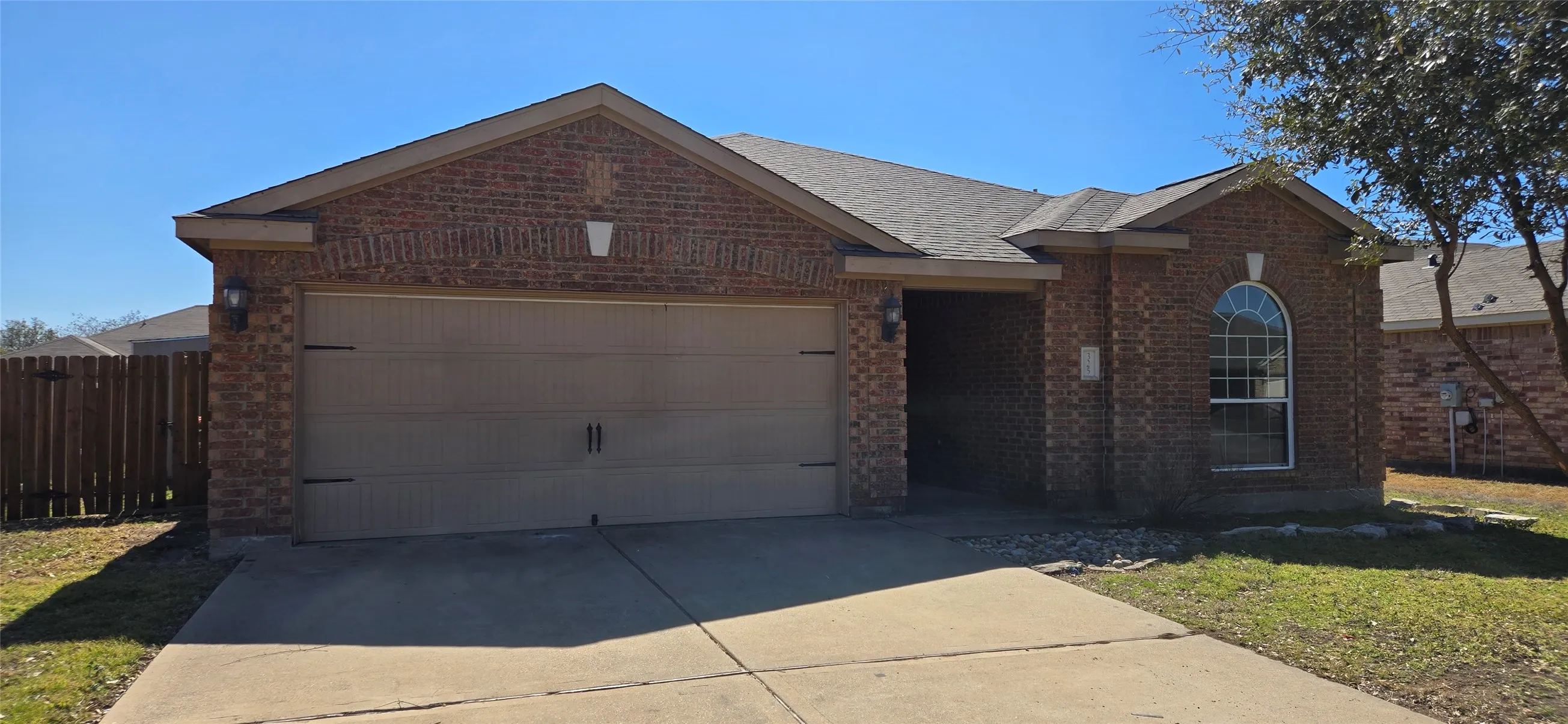 View of front of home featuring concrete driveway, roof with shingles, fence, an attached garage, and brick siding