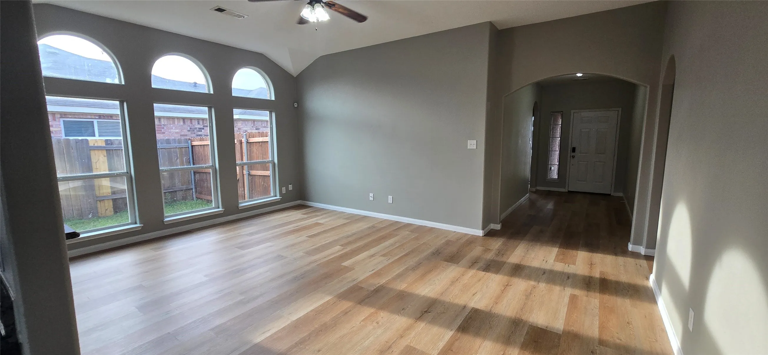 Spare room featuring arched walkways, ceiling fan, visible vents, and wood finished floors