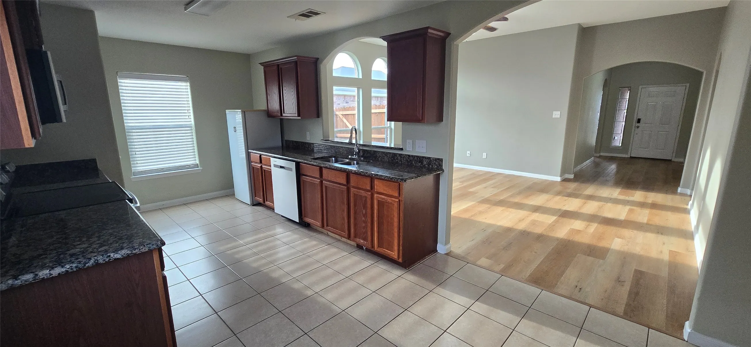 Kitchen with stainless steel dishwasher, a sink, arched walkways, visible vents, and range with electric cooktop