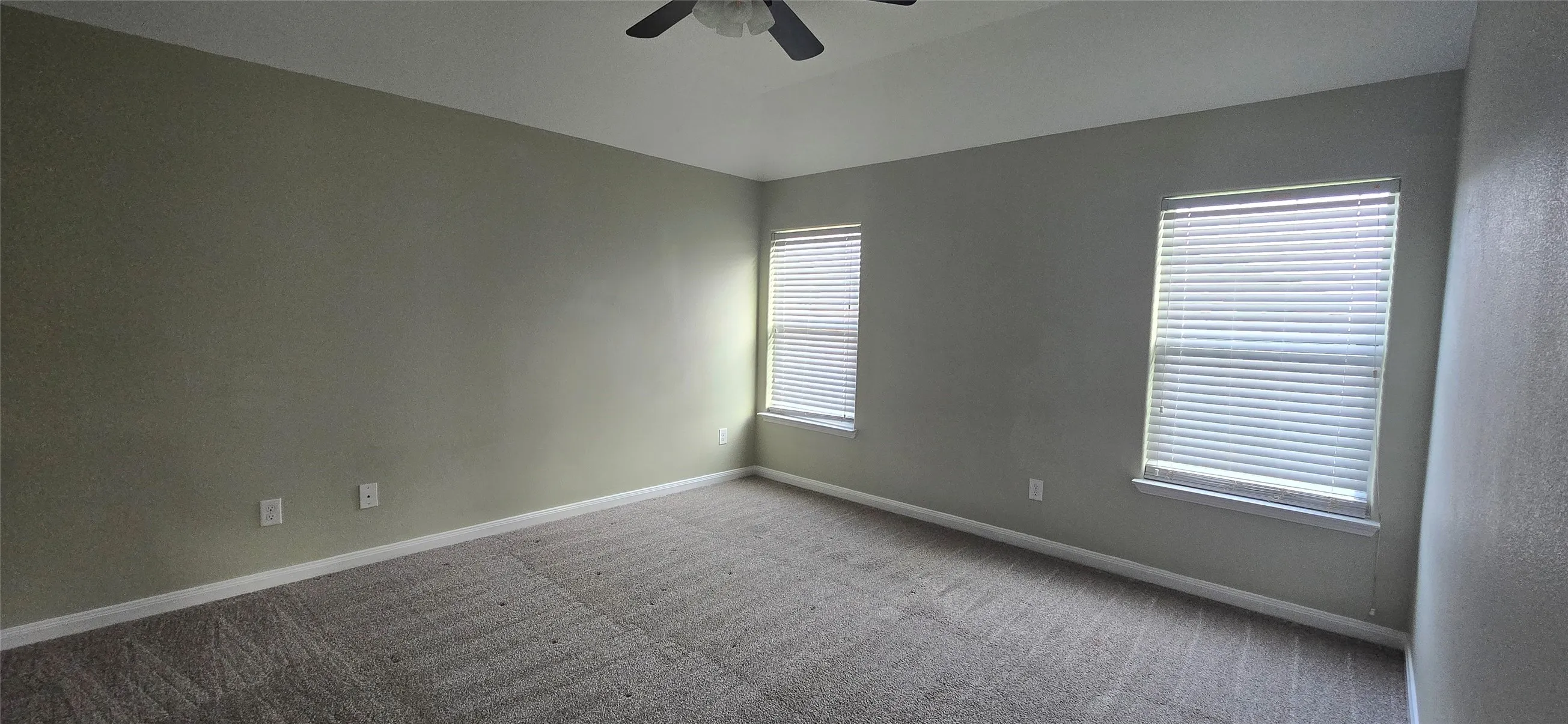 Empty room featuring carpet, baseboards, vaulted ceiling, and ceiling fan