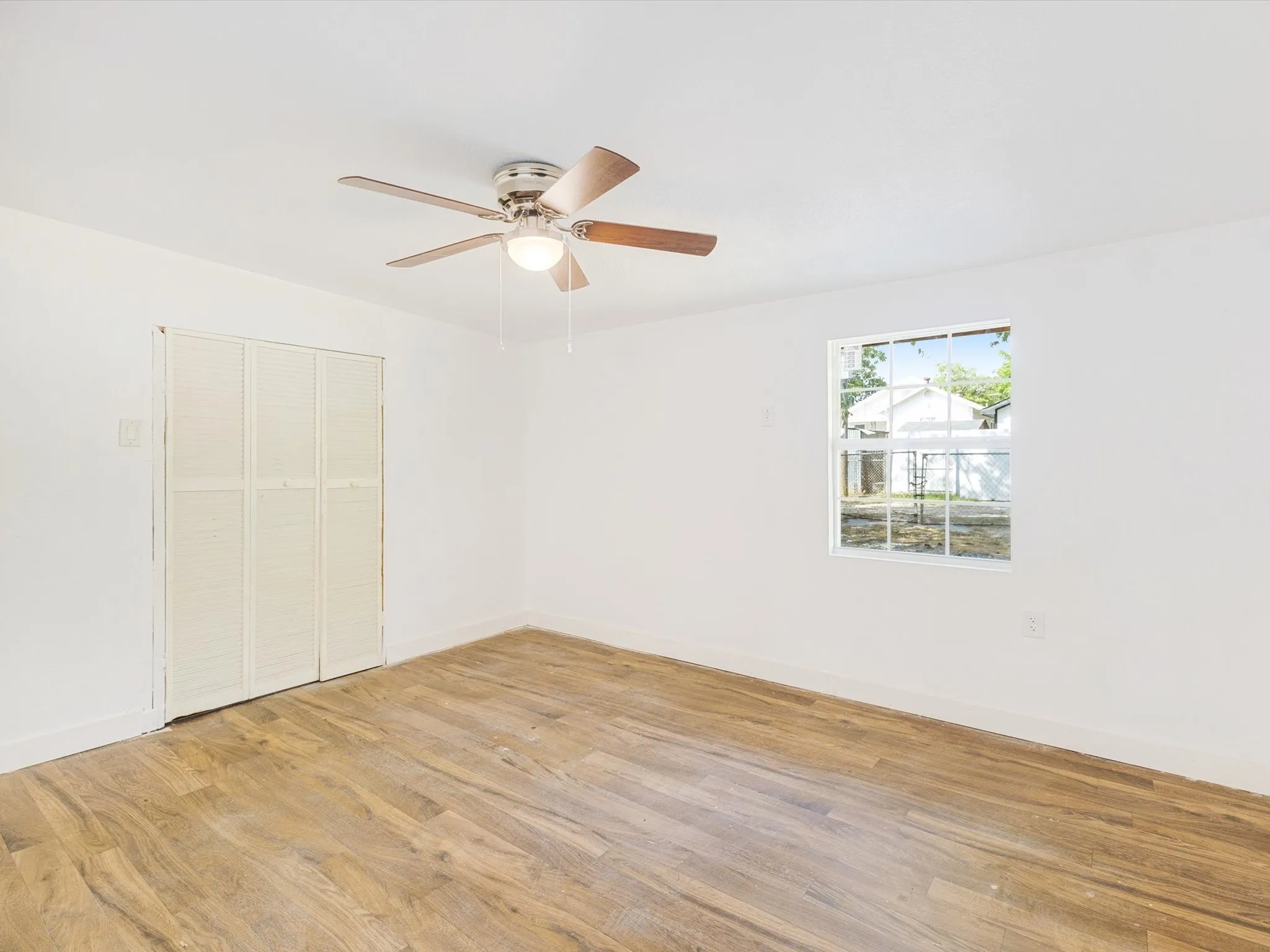 Wood-finish flooring, white walls, and a ceiling fan with light fixture