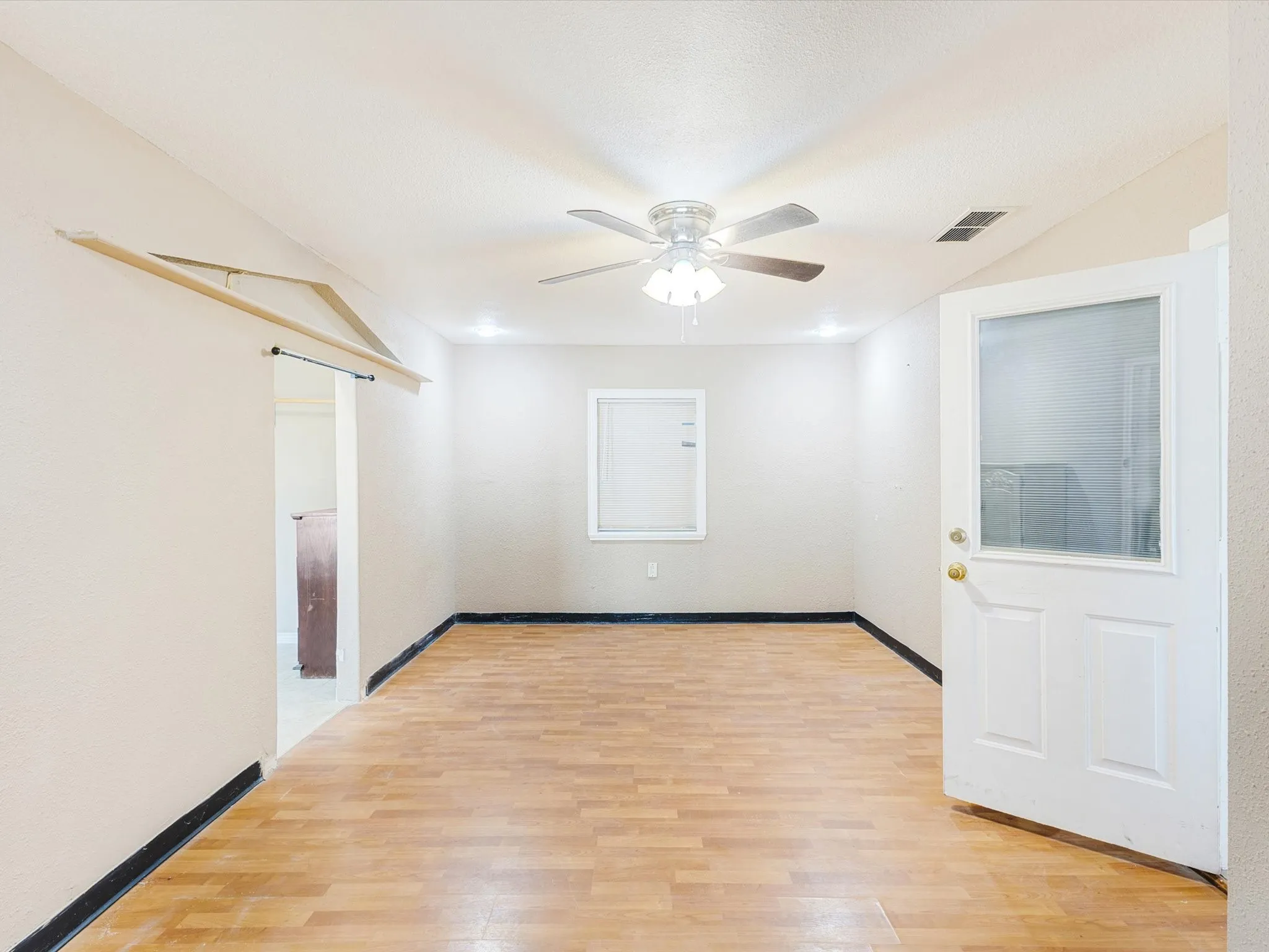 Wood-finish flooring, ceiling fan, recessed lighting, white interior door with glass panel, and a barn door entry