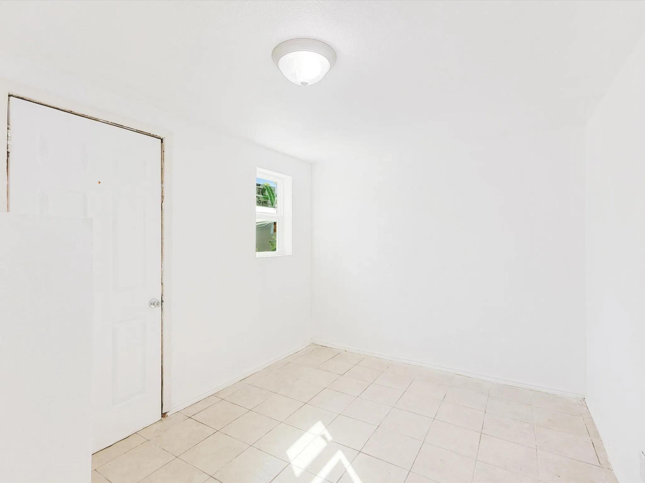 White interior walls, tile flooring, flush mount ceiling lighting, and a single window