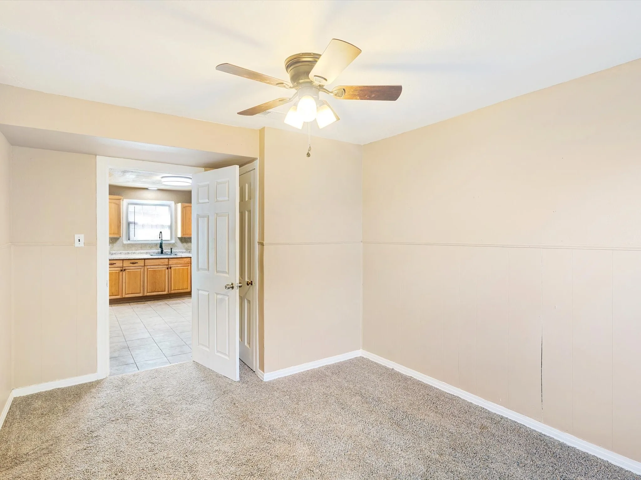 Spacious bedroom with neutral wall finishes, carpeted flooring, and ceiling fan with integrated lighting