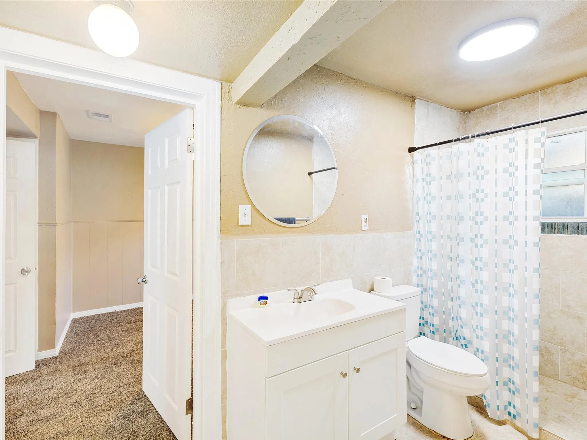 Bathroom featuring a white vanity with integrated sink, a circular wall mirror, and a toilet