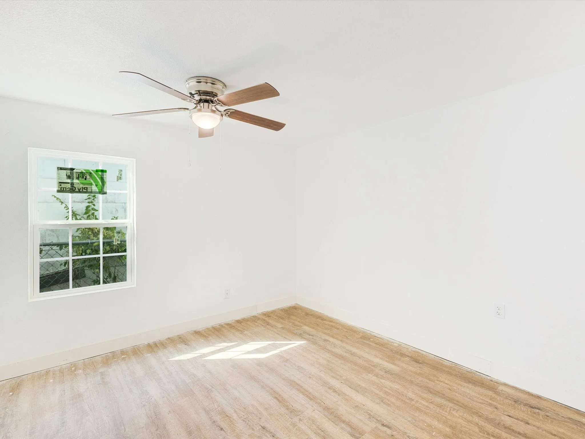 Wood-finish flooring, white walls, and a ceiling fan with integrated lighting
