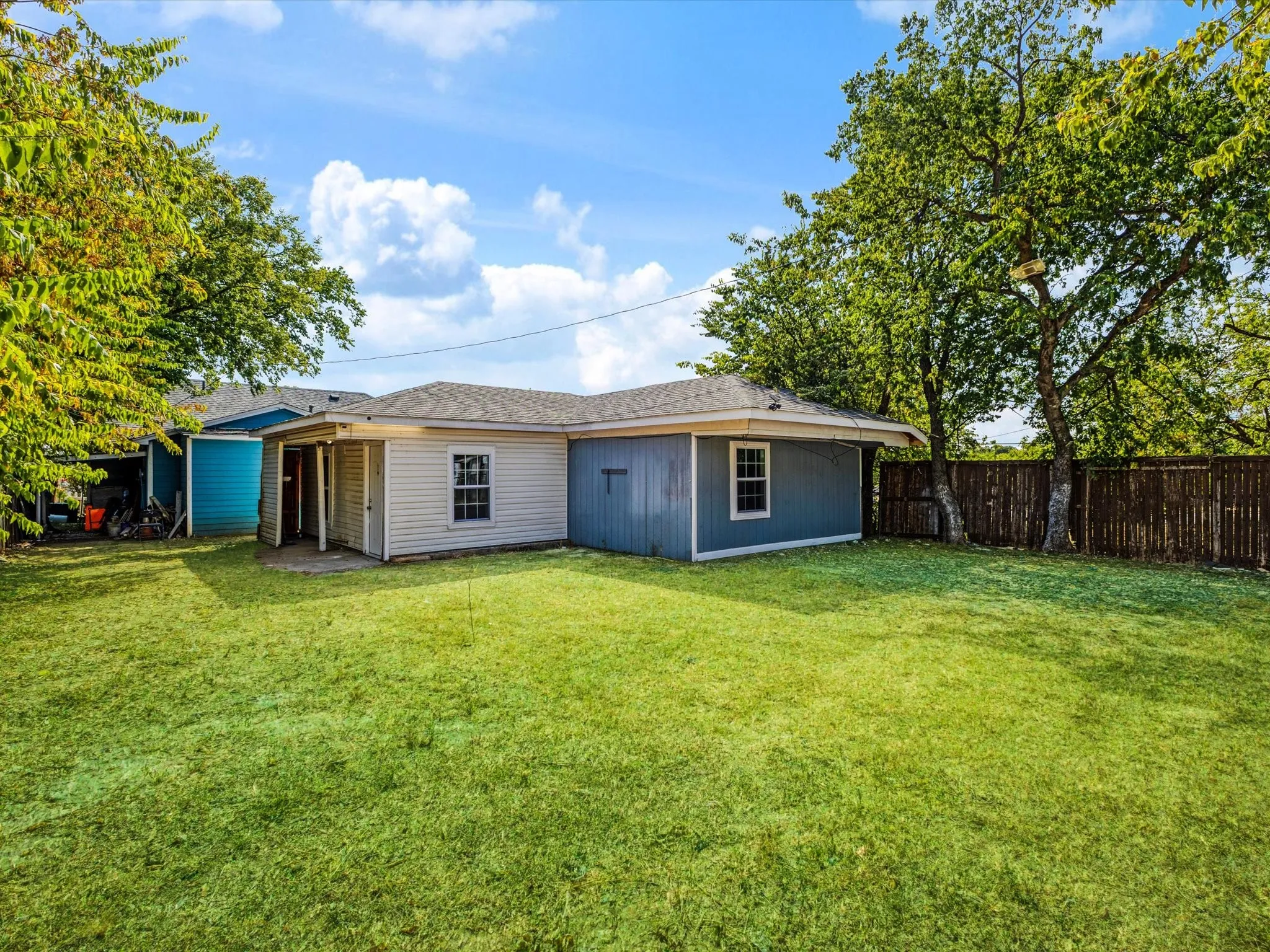 Expansive lawn area with mature trees and a wood privacy fence