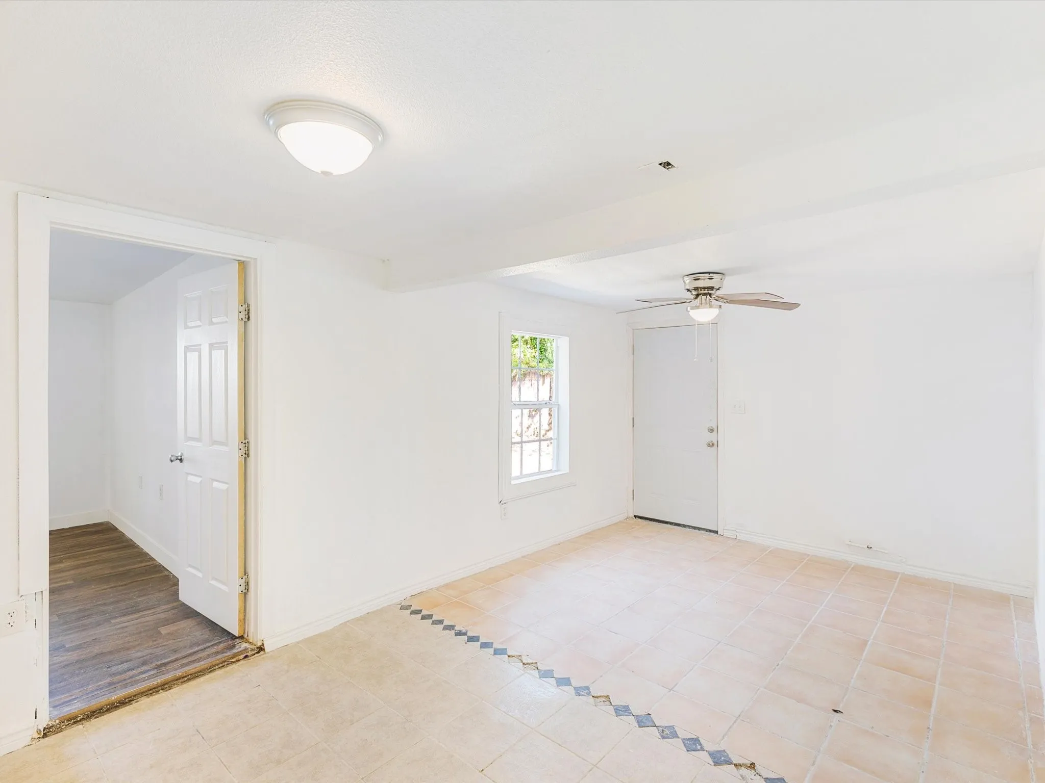 Recessed ceiling light fixture, wood-finish flooring, tiled flooring with accent border, and a ceiling fan with integrated lighting