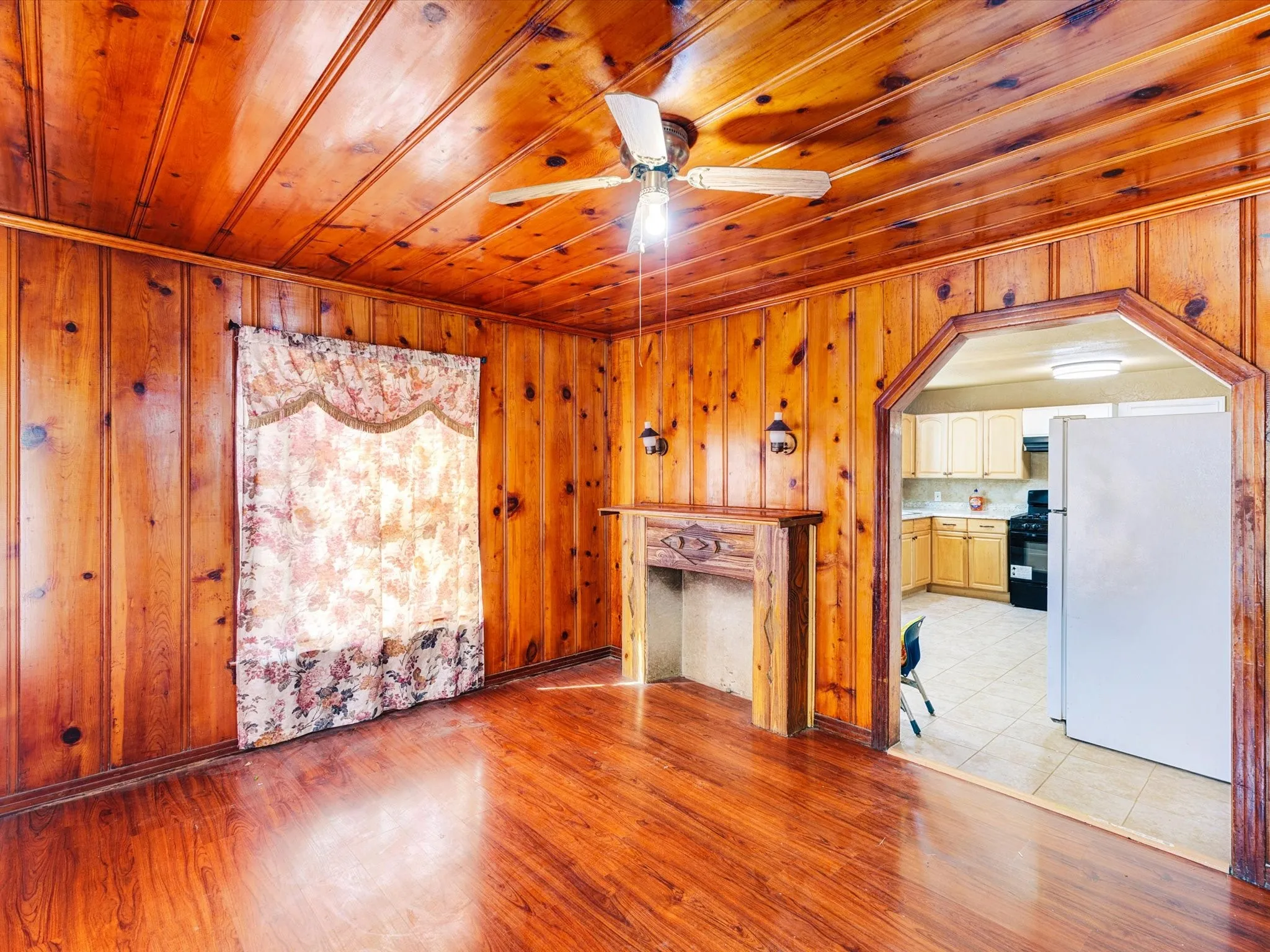 Warm knotty pine wood paneling throughout this spacious room, complemented by matching wood ceiling with ceiling fan