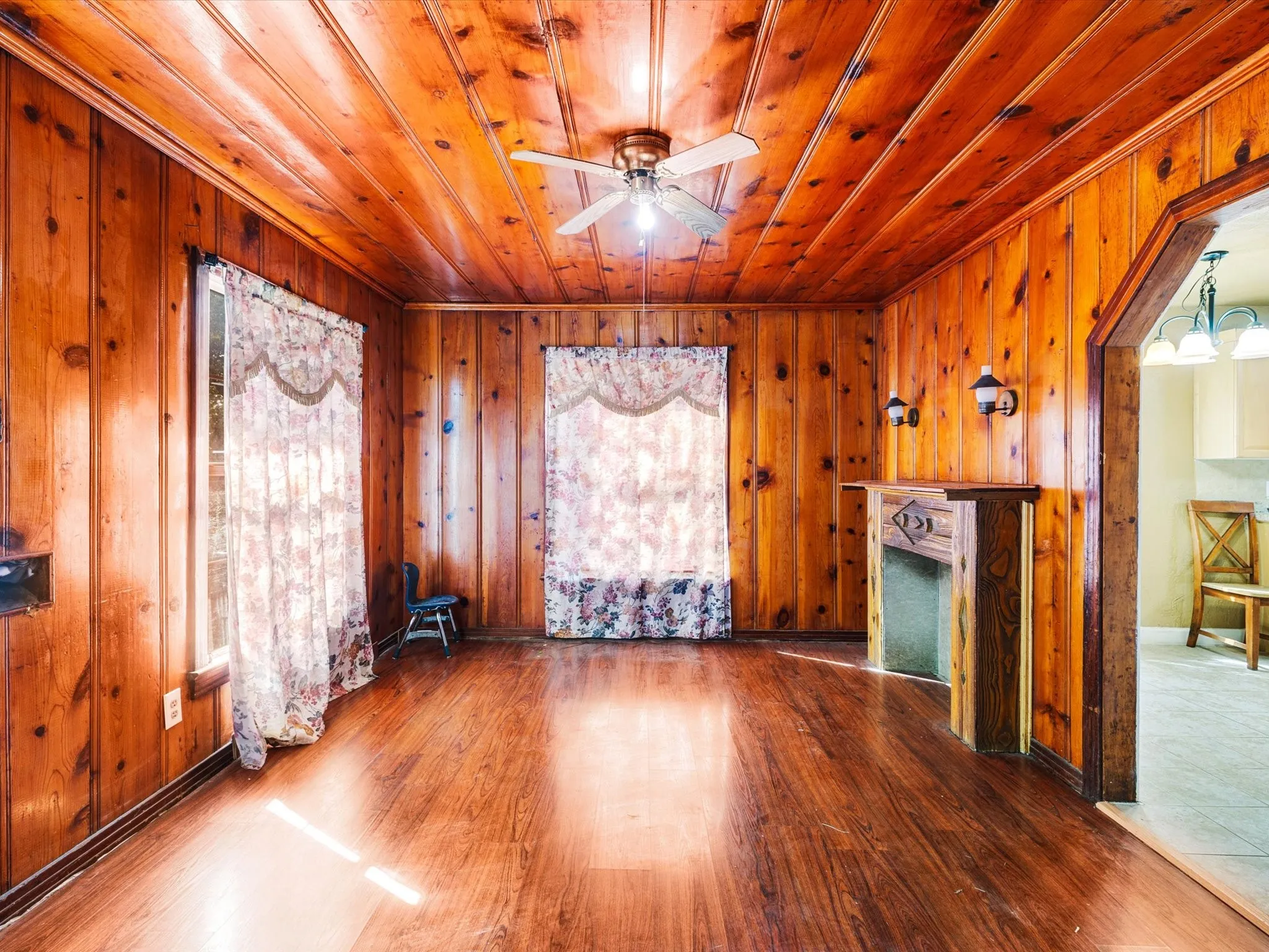 Wood-paneled walls and ceiling, wood-finish flooring, and a decorative fireplace