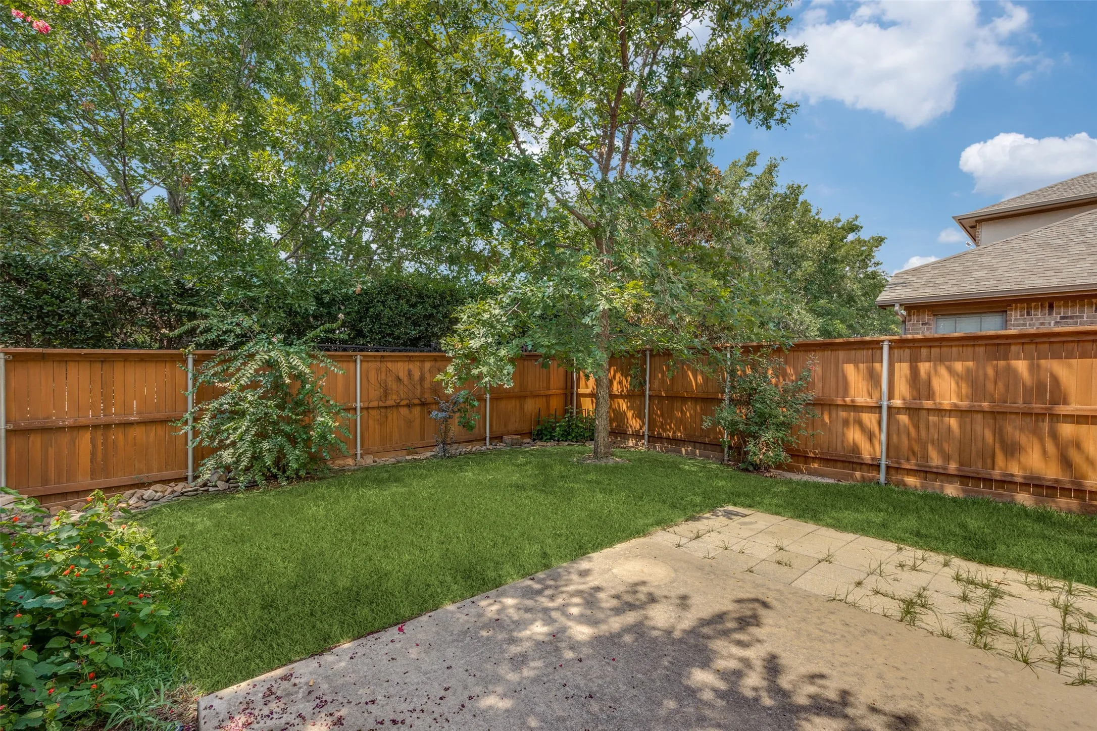 Private fenced backyard with a concrete patio and established trees